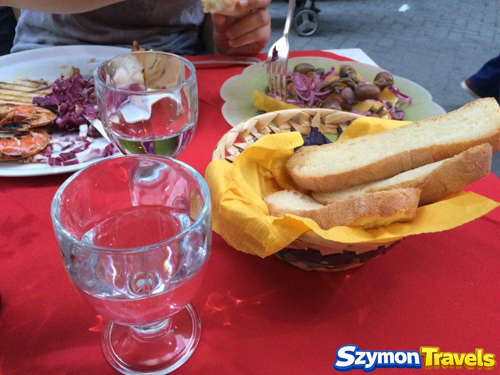 Stół z pieczywem, oliwkami, wodą i grillowanymi owocami morza w Syrakuzach