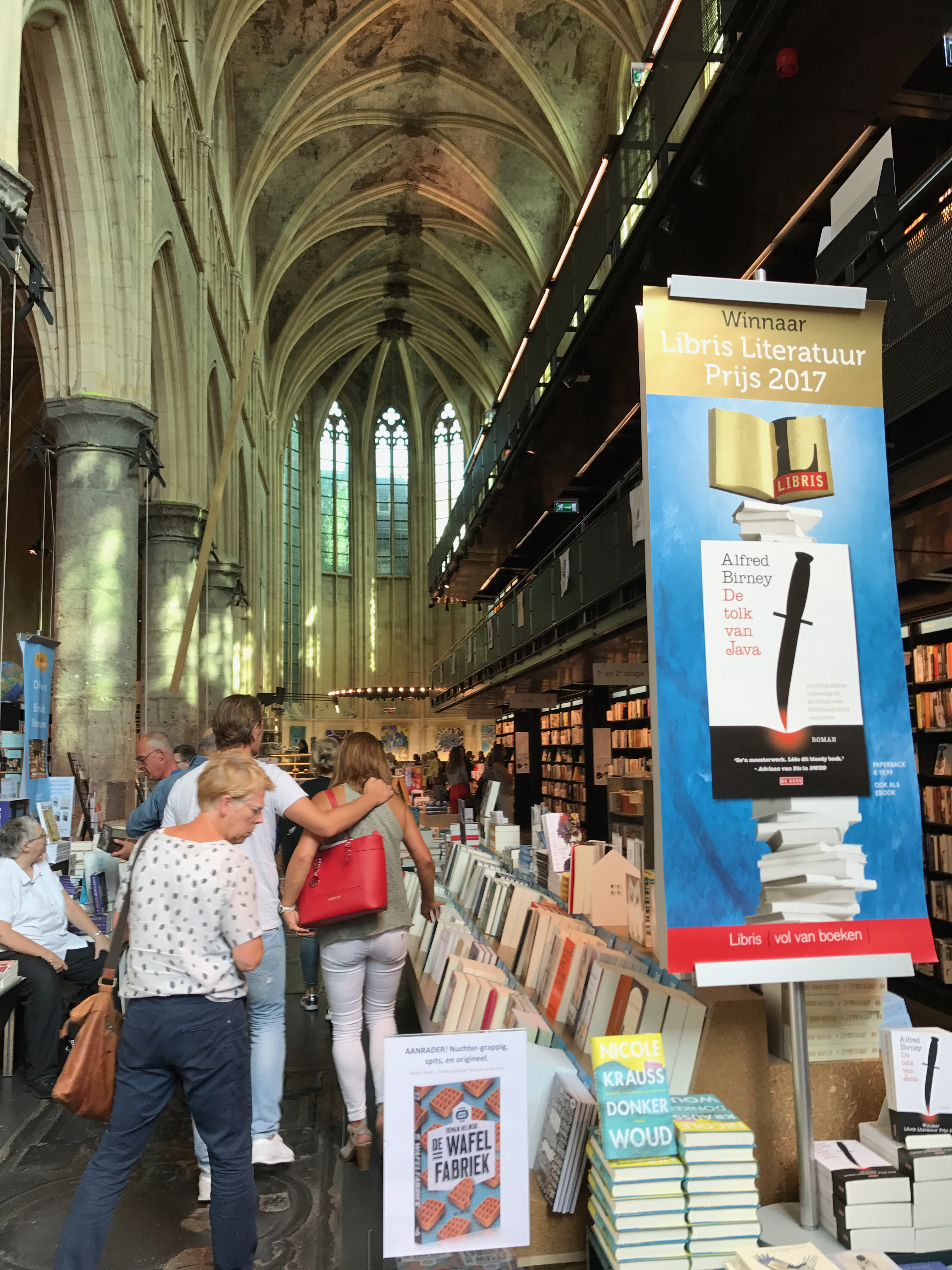 Wnętrze Boekhandel Dominicanen w Maastricht, księgarni urządzonej w dawnym kościele dominikanów, z wysokimi sklepieniami i regałami książek.