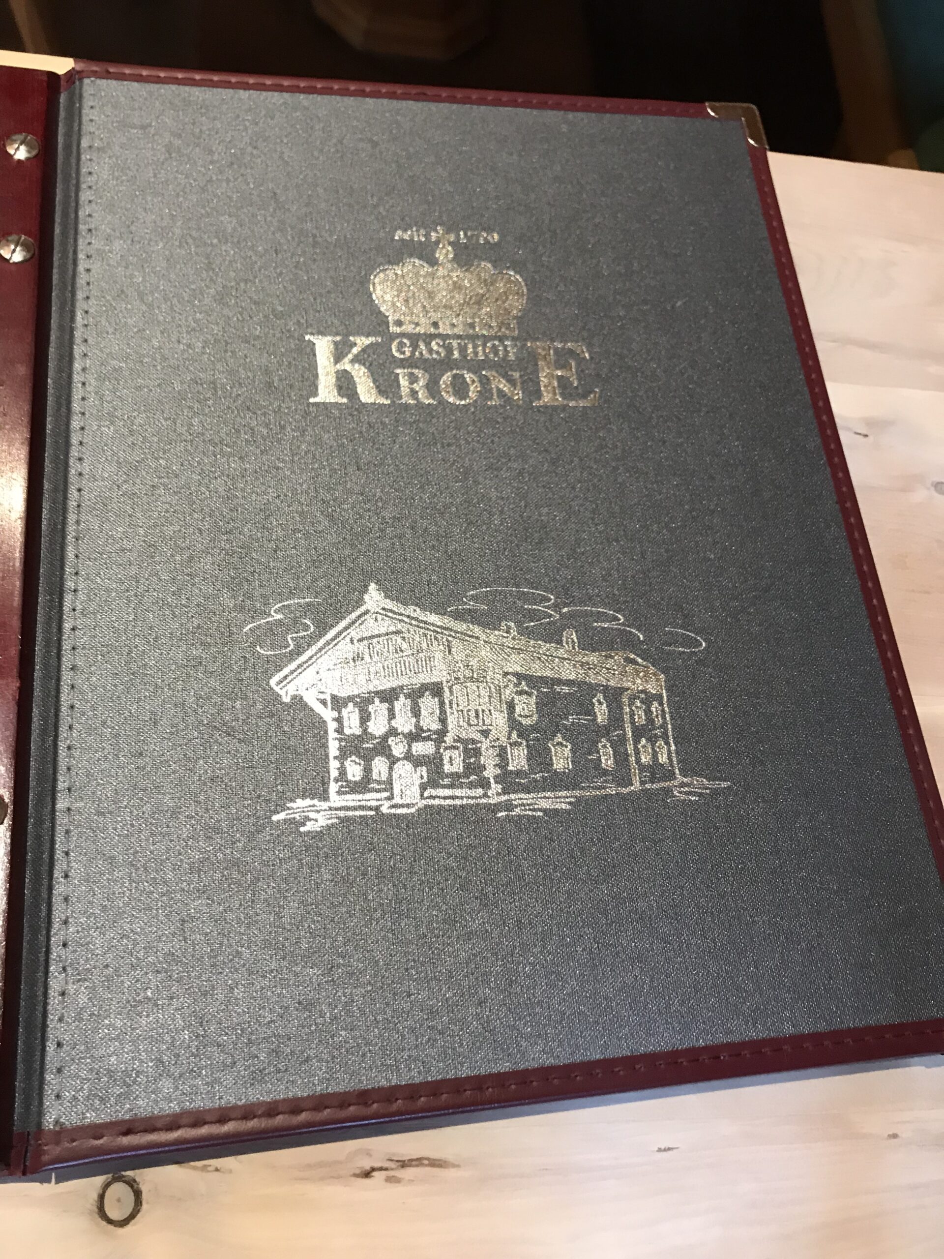 Menu Gasthof Krone w Umhausen Karta menu Gasthof Krone w Umhausen z logo korony i rysunkiem tradycyjnego budynku.
