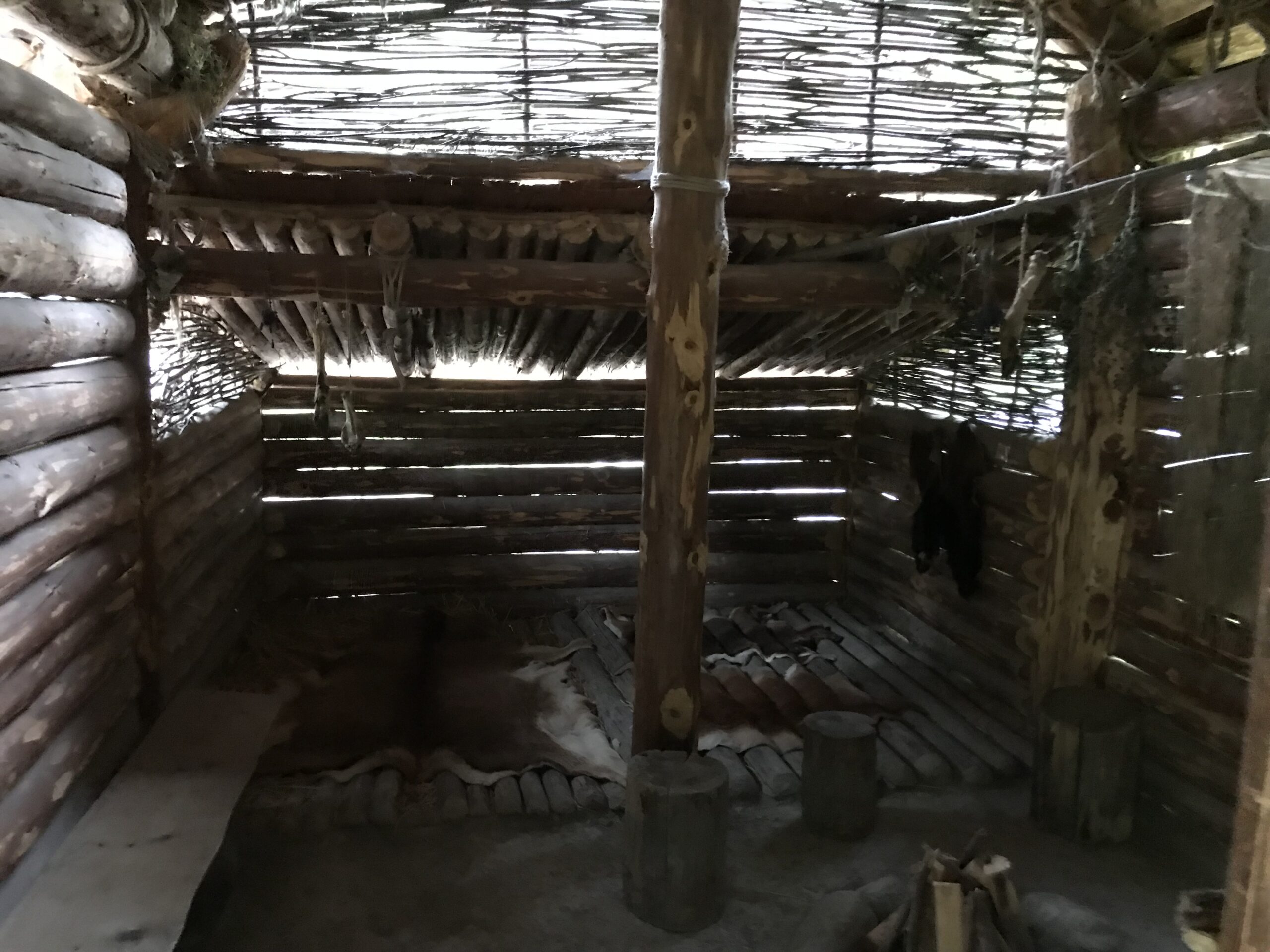 Wnętrze rekonstrukcji chaty w Ötzi-Dorf Wnętrze rekonstrukcji prehistorycznej chaty w Ötzi-Dorf z drewnianymi ścianami, plecionym dachem, skórami i paleniskiem.