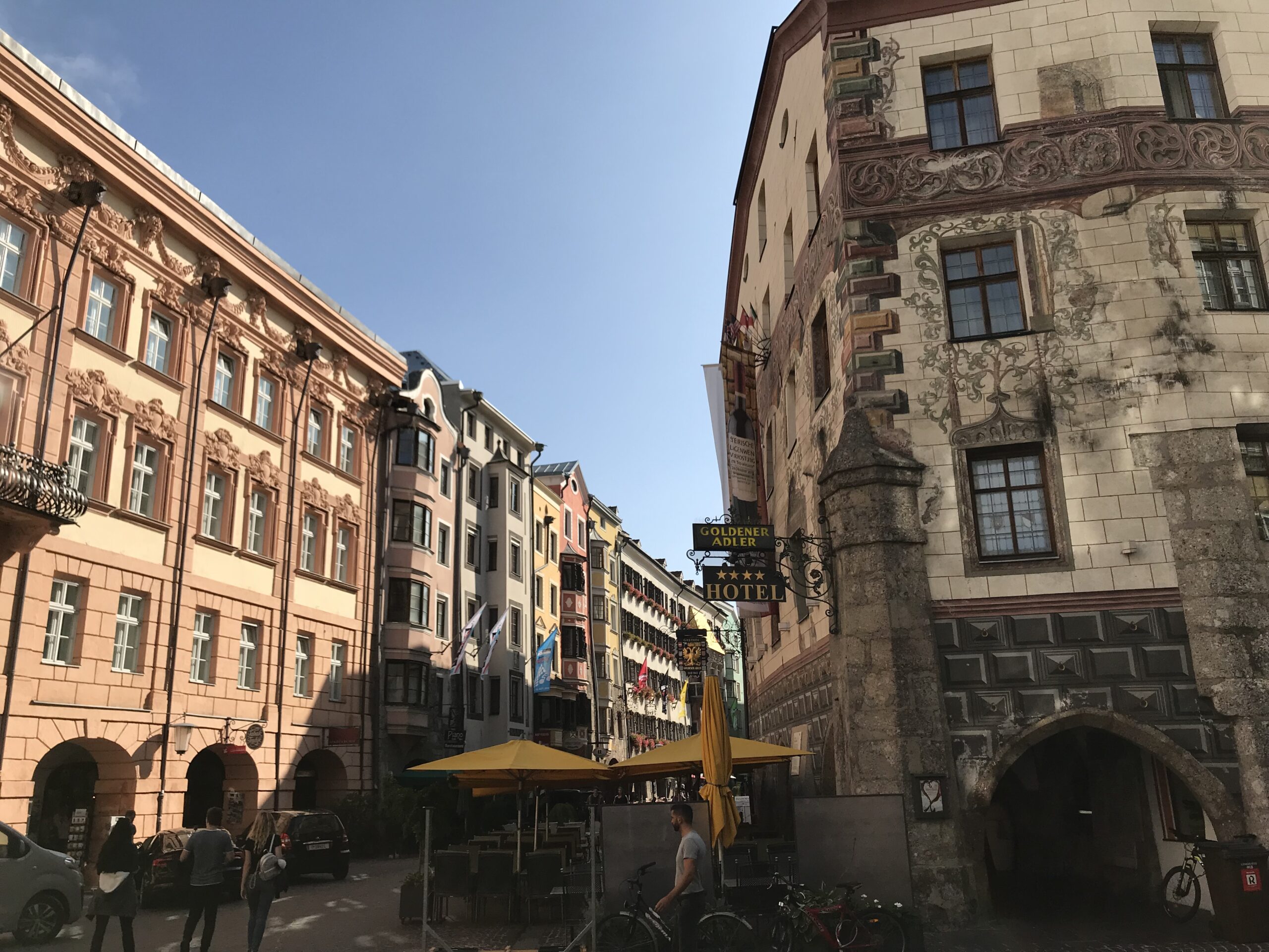 Stare miasto w Innsbrucku i Hotel Goldener Adler Stare miasto w Innsbrucku z malowaną fasadą historycznego budynku, szyldem Hotel Goldener Adler i kawiarnianymi stolikami