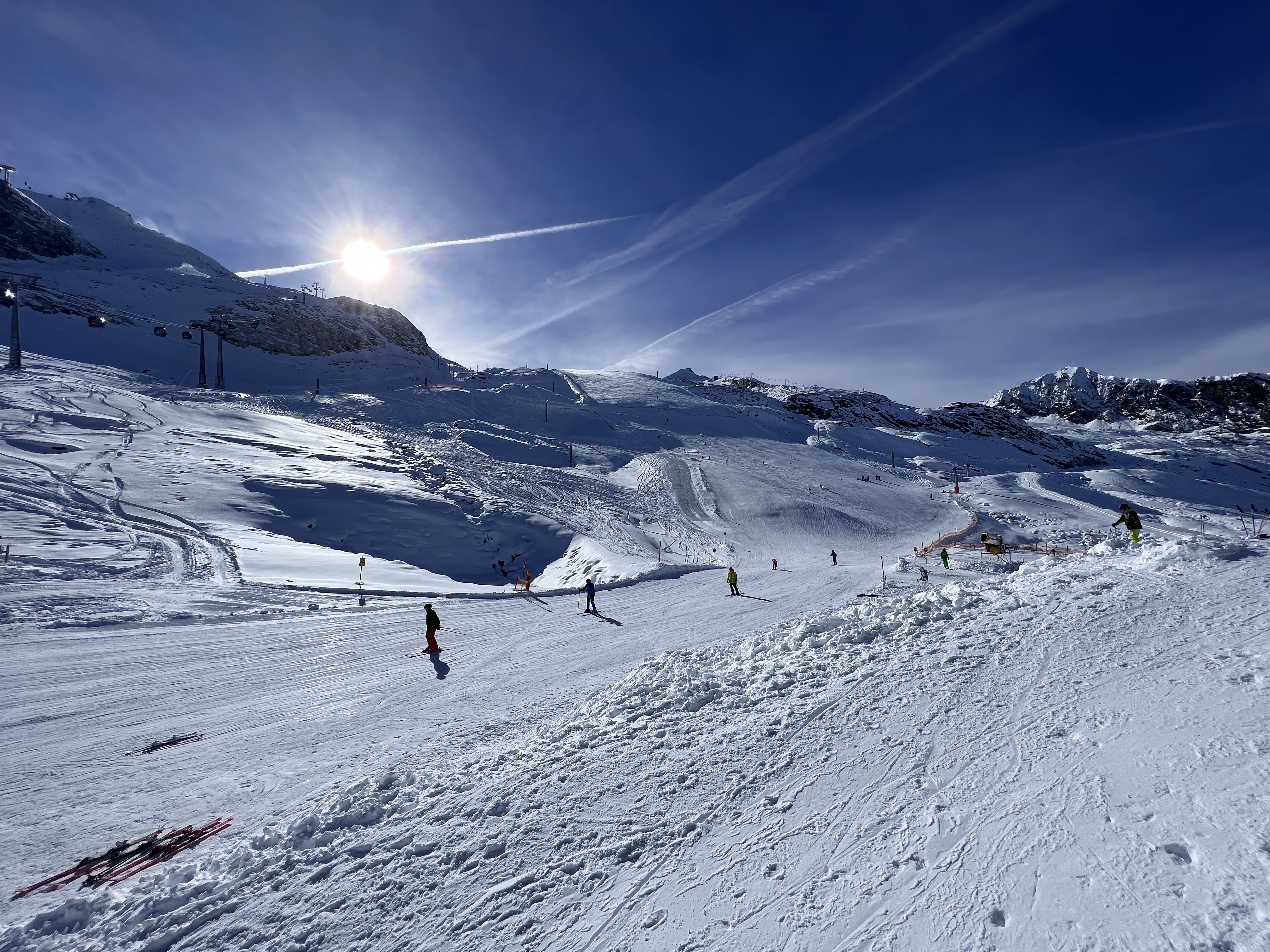 Słoneczna trasa narciarska w Ski Zillertal 3000 Narciarze na szerokiej ośnieżonej trasie w rejonie Ski Zillertal 3000 przy silnym słońcu i górskiej panoramie