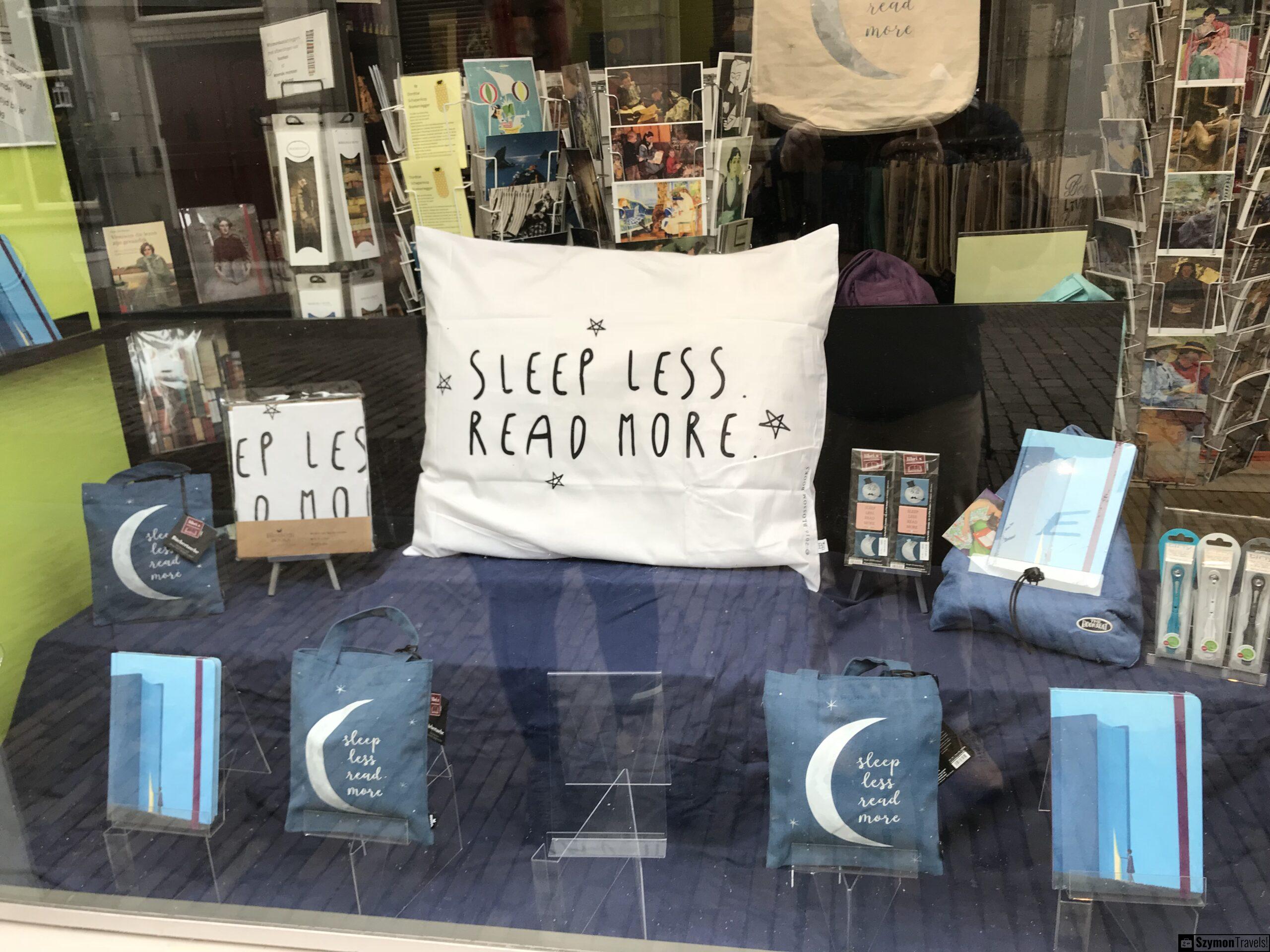 Witryna sklepu z napisem Sleep less. Read more w Dordrecht Witryna sklepu w Dordrecht z dużą białą poduszką z napisem Sleep less. Read more, książkami, torbami i drobnymi prezentami.