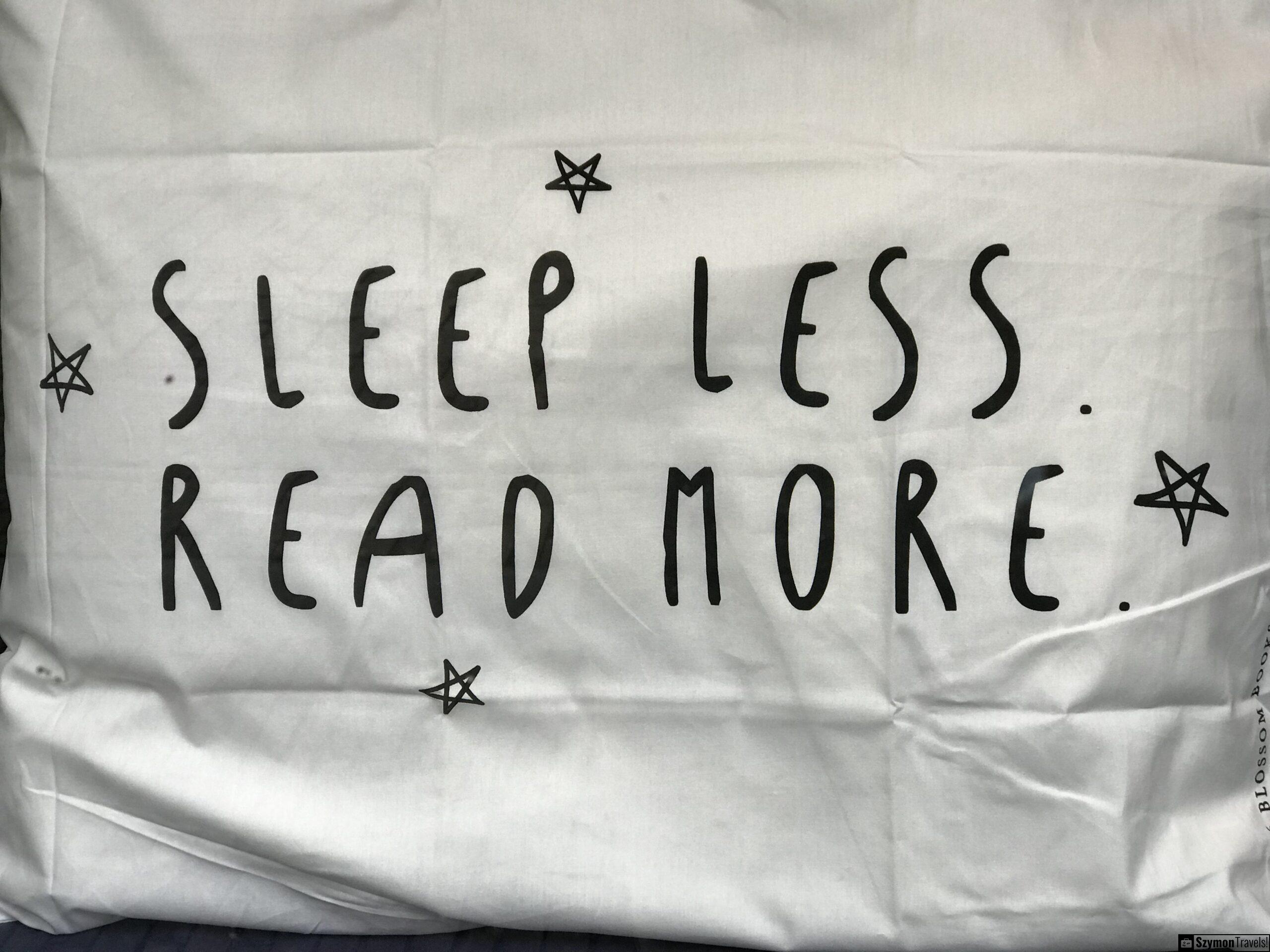 Sleep less. Read more – detal z witryny w Dordrecht Zbliżenie na białą poduszkę z napisem Sleep less. Read more w witrynie sklepu w Dordrecht.