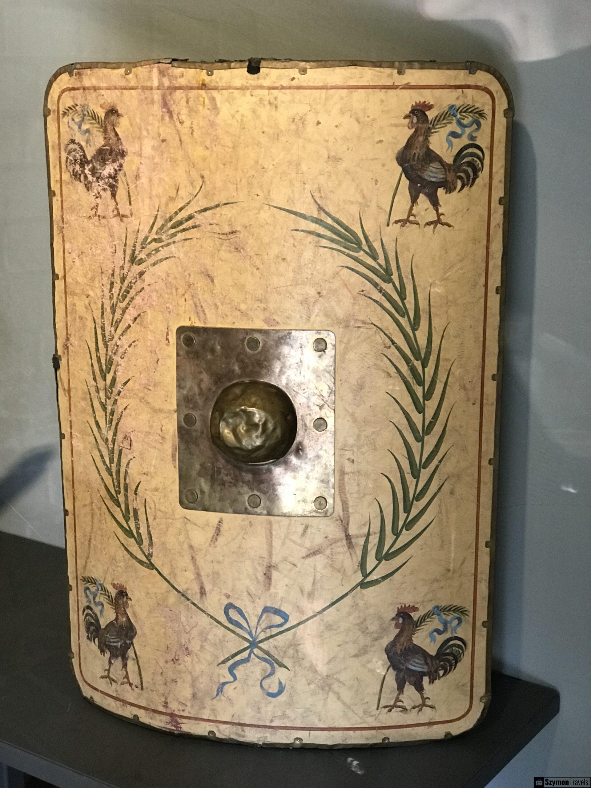 Dekorowana rzymska tarcza z kogutami w muzeum w Xanten Dekorowana rzymska tarcza lub element ochronny z malowanymi kogutami, wieńcem i metalowym umbo w muzeum w Xanten