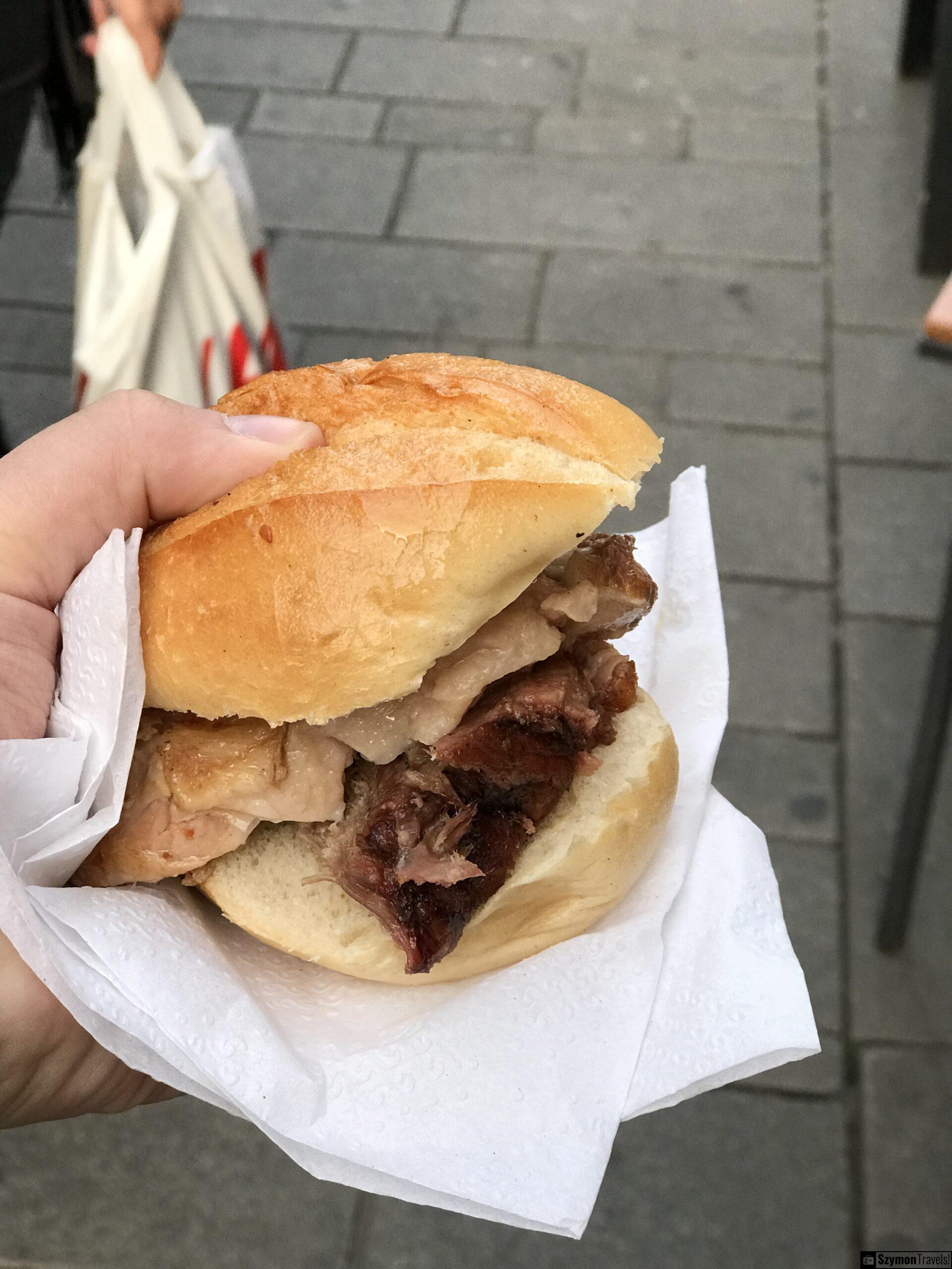 Bułka z pieczonym mięsem w Düsseldorfie Bułka z pieczonym mięsem trzymana w ręku na ulicy w Düsseldorfie