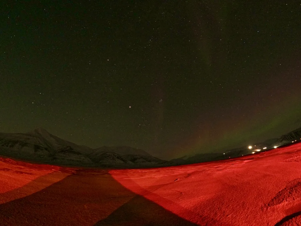 An icy wasteland illuminated by the lights of a snow cat