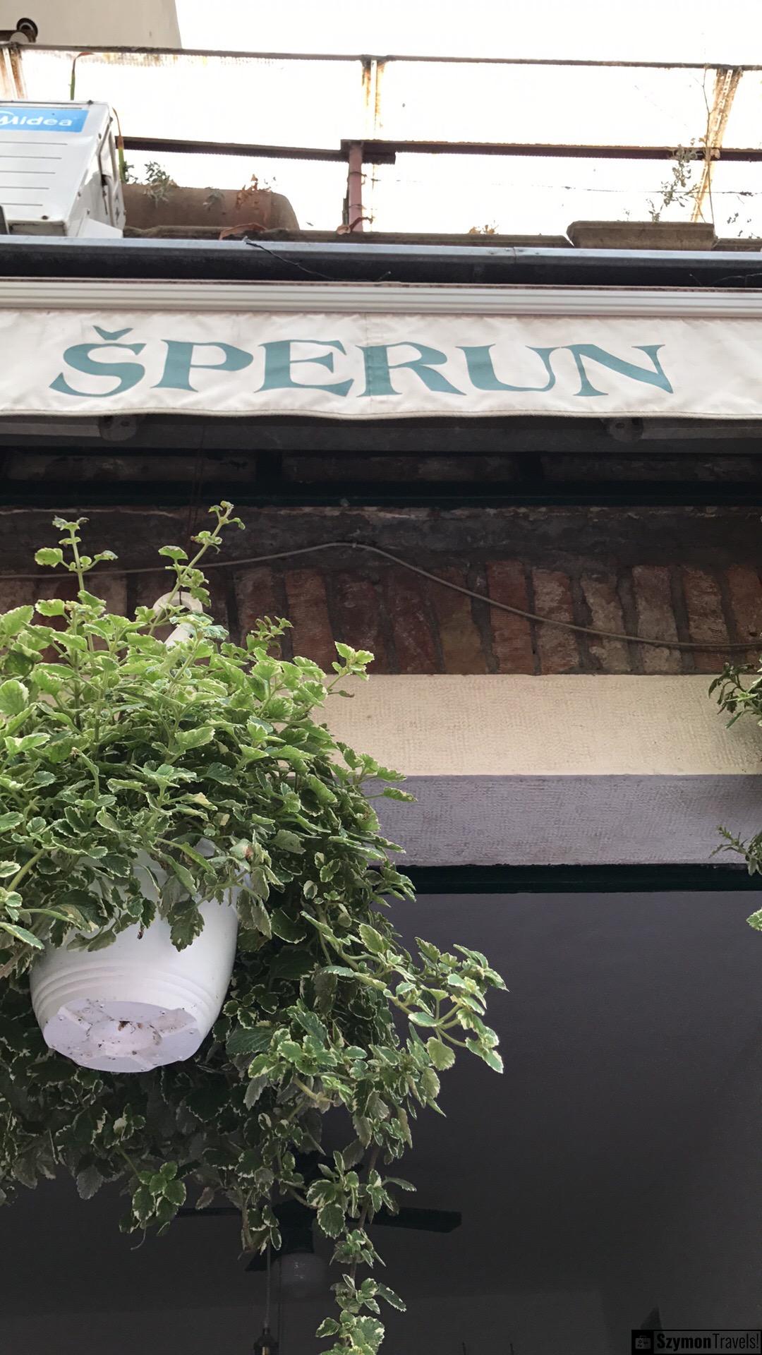 Szyld restauracji Šperun w Splicie Szyld restauracji Šperun w Splicie z wiszącą rośliną przy wejściu i fragmentem starej fasady.