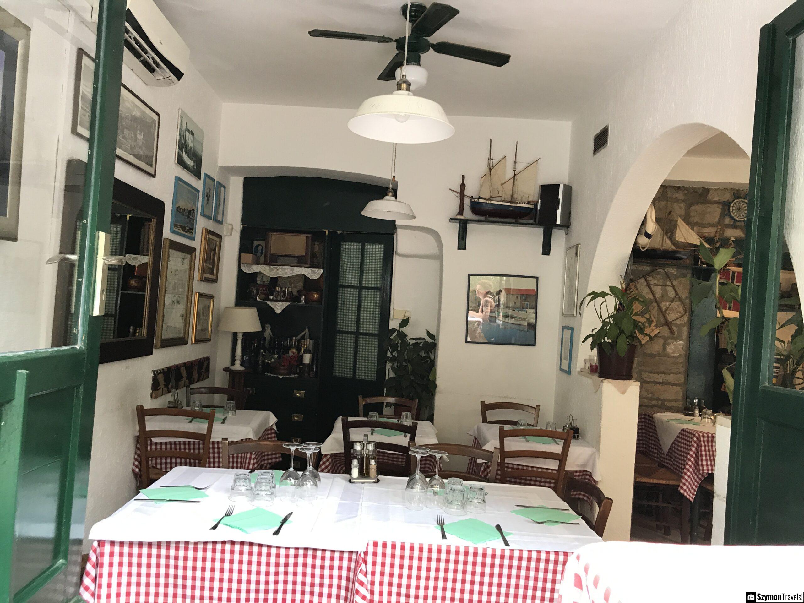 Wnętrze restauracji Šperun w Splicie Wnętrze restauracji Šperun w Splicie z białymi ścianami, zielonymi drzwiami, czerwono-białymi obrusami i modelami statków.