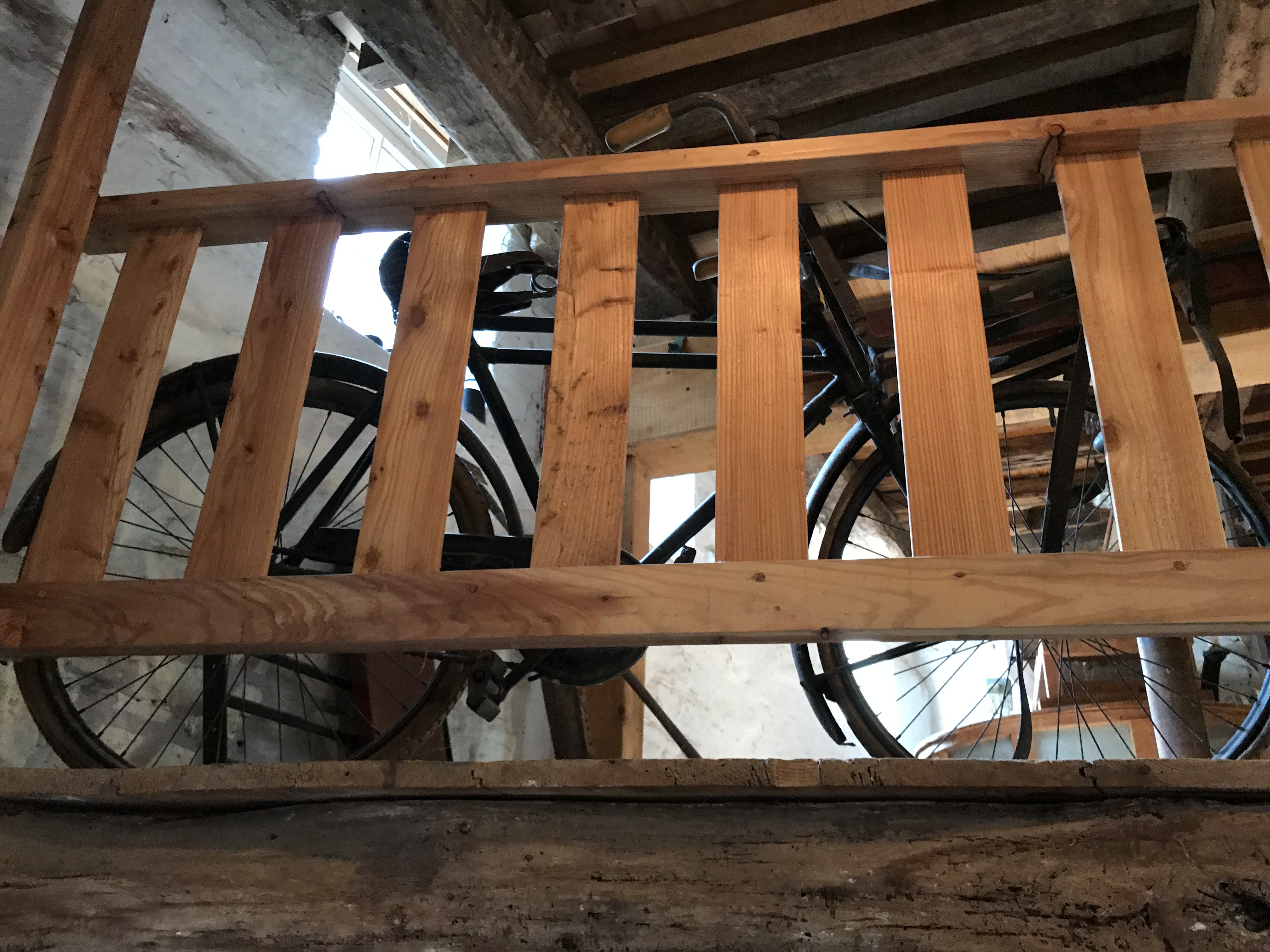 Fragment ekspozycji w De Bisschopsmolen w Maastricht z rowerem widocznym za drewnianą balustradą we wnętrzu młyna.