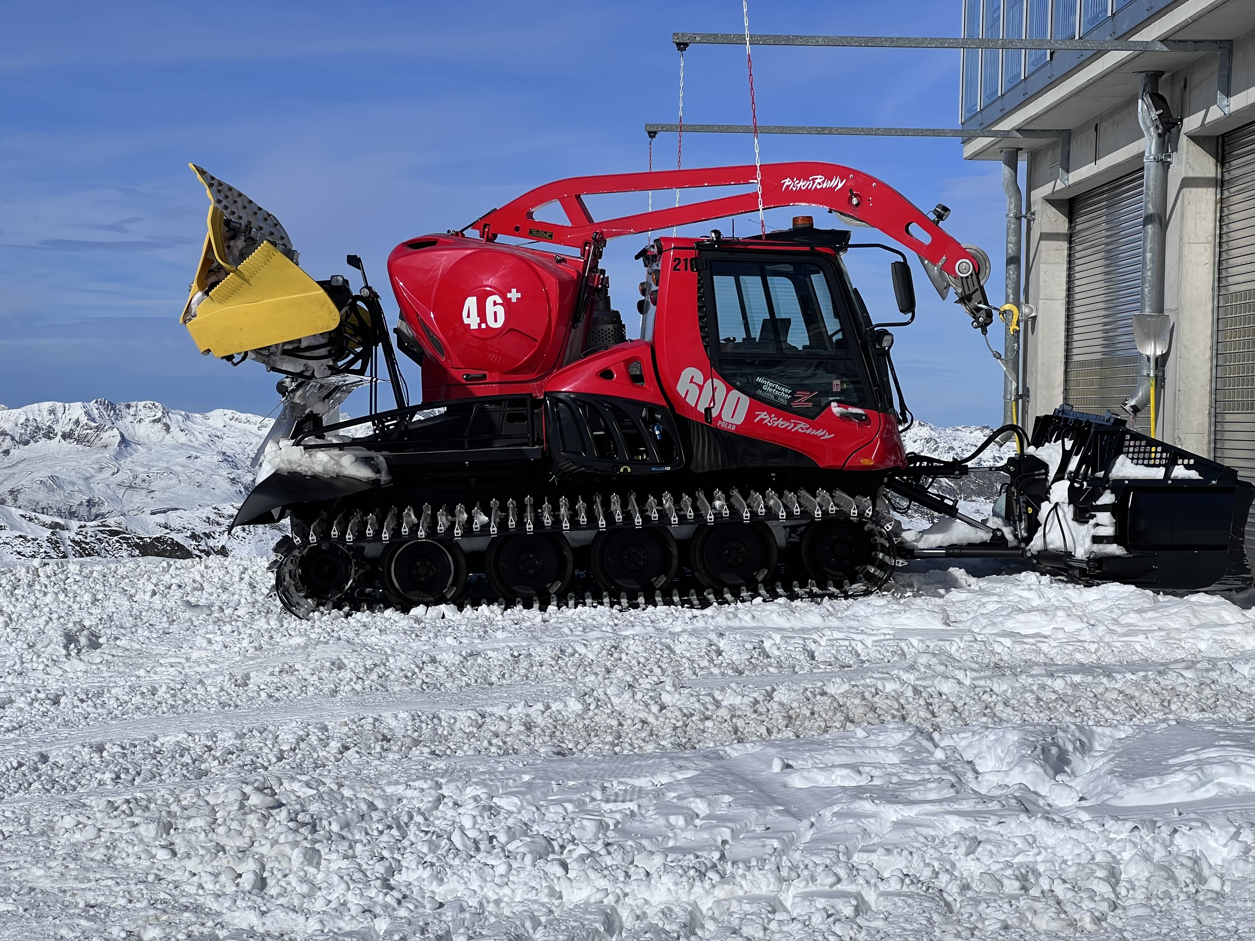 Ratrak PistenBully na lodowcu Hintertux Czerwony ratrak PistenBully na śniegu przy stacji na lodowcu Hintertux w Tyrolu