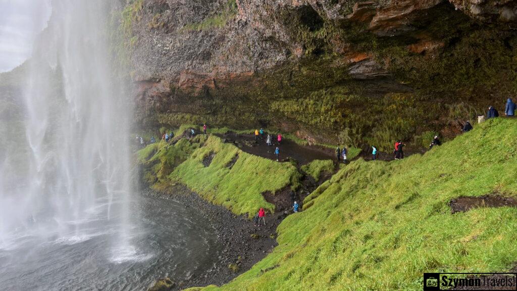 Widok na ludzi i jaskinie za wodospadem Seljalandsfoss, Islandia Widok na jaskinie za wodospadem Seljalandsfoss, Islandia