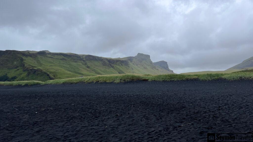 Widok z czarnej plaży na zielone wzgórza w Vik, Islandia Widok z czarnej plaży w Vik, Islandia