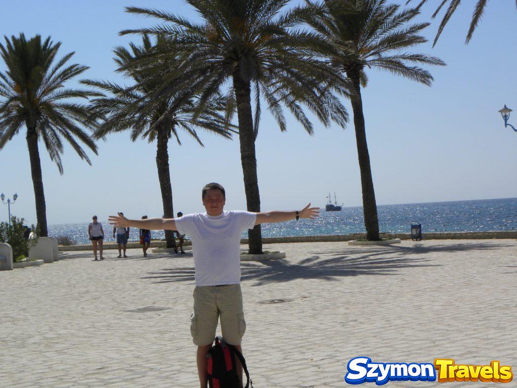 Szymon na promenadzie w Hammamecie z palmami i Morzem Śródziemnym w tle