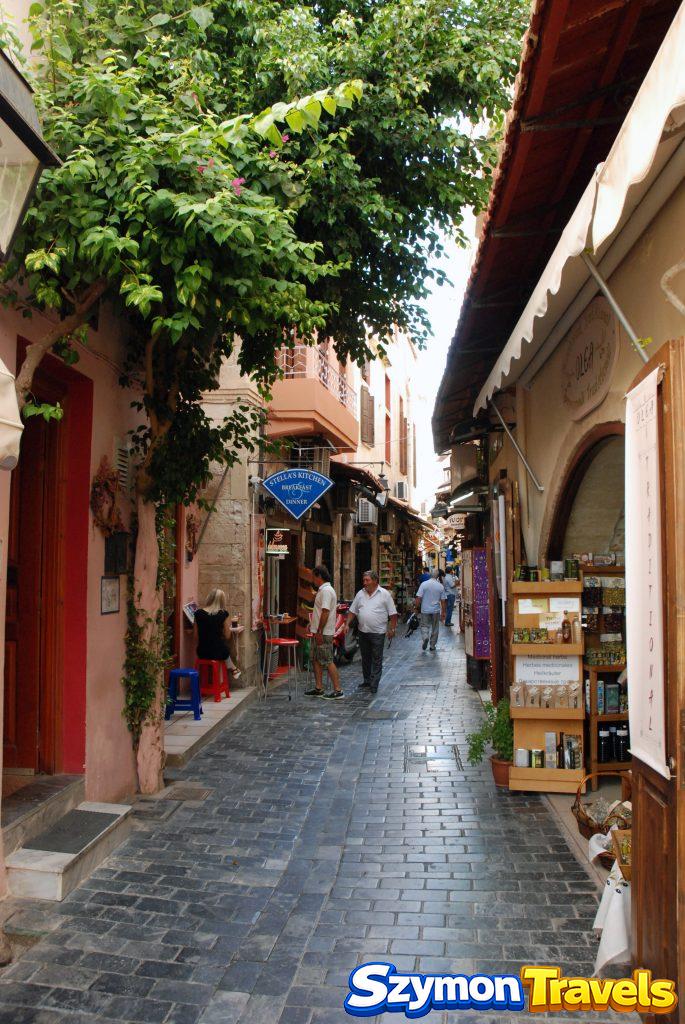 Wąska uliczka starego miasta Rethymno z restauracjami, sklepami i drzewem dającym cień