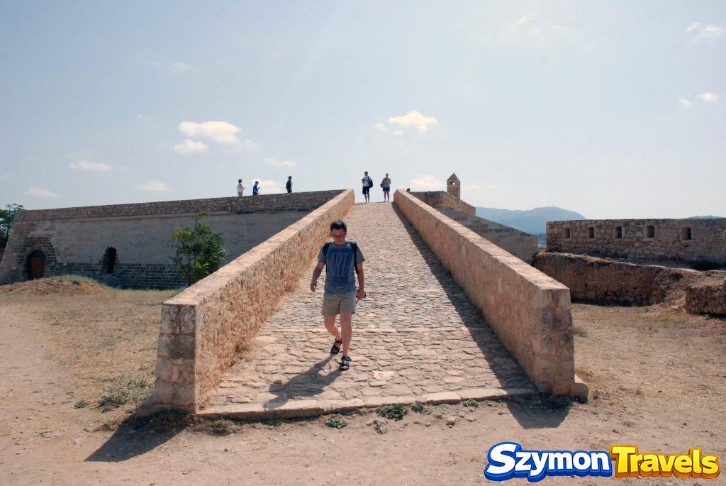 Kamienna rampa i mury Fortezzy w Rethymno z turystą schodzącym w dół