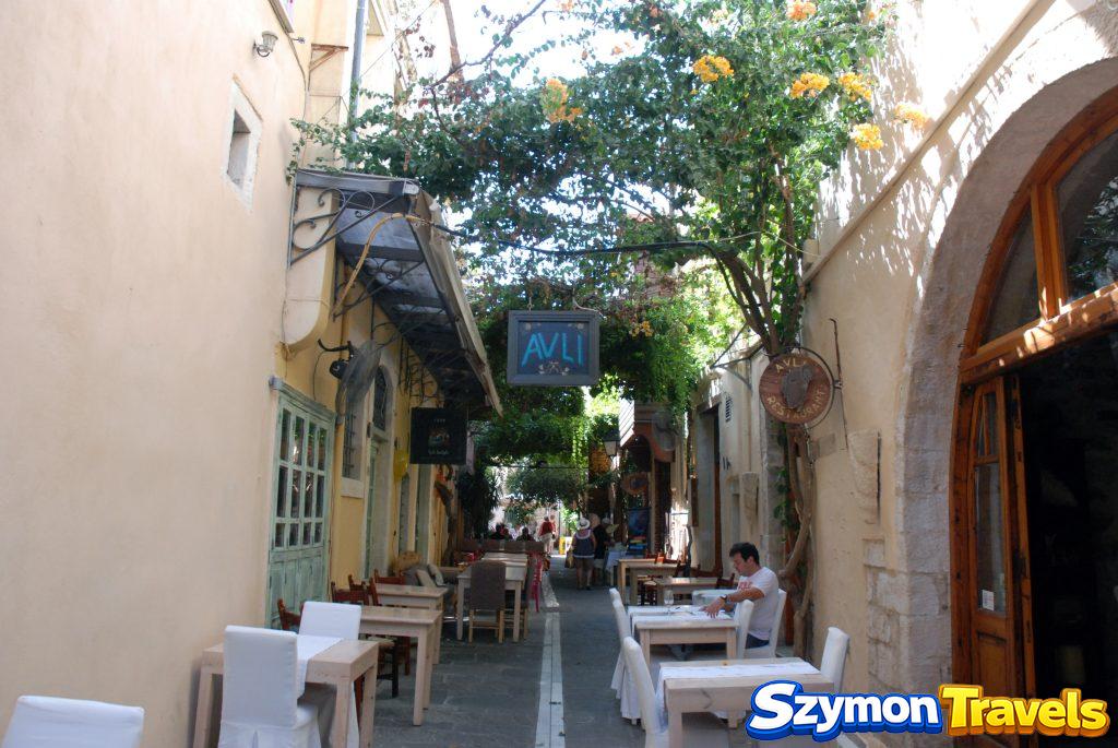 Restauracyjna uliczka Avli w starym mieście Rethymno z drewnianymi stolikami i roślinnością