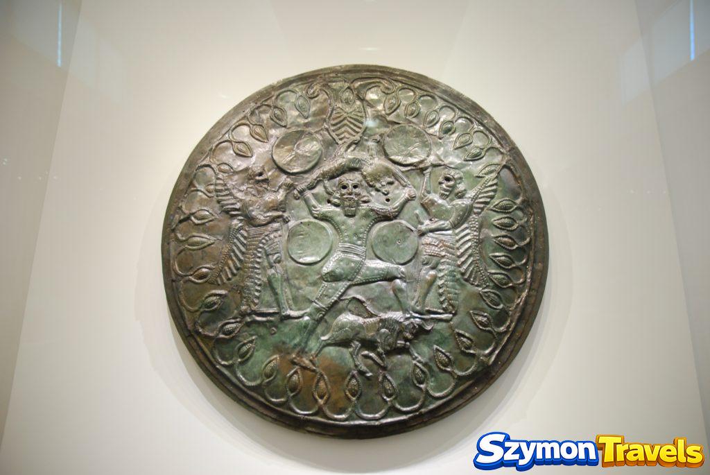Dekorowana brązowa tarcza z postaciami i zwierzętami na wystawie Muzeum Archeologicznego w Heraklionie