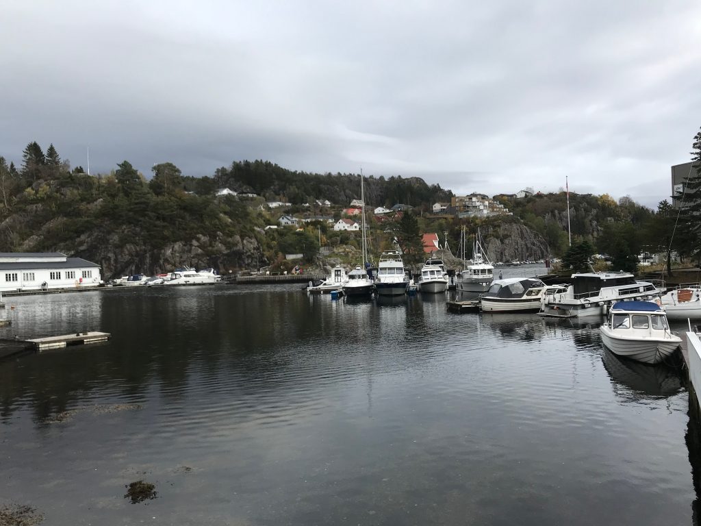 Port w Strusshamn z łodziami na wodzie i domami na skalistych wzgórzach Askøy