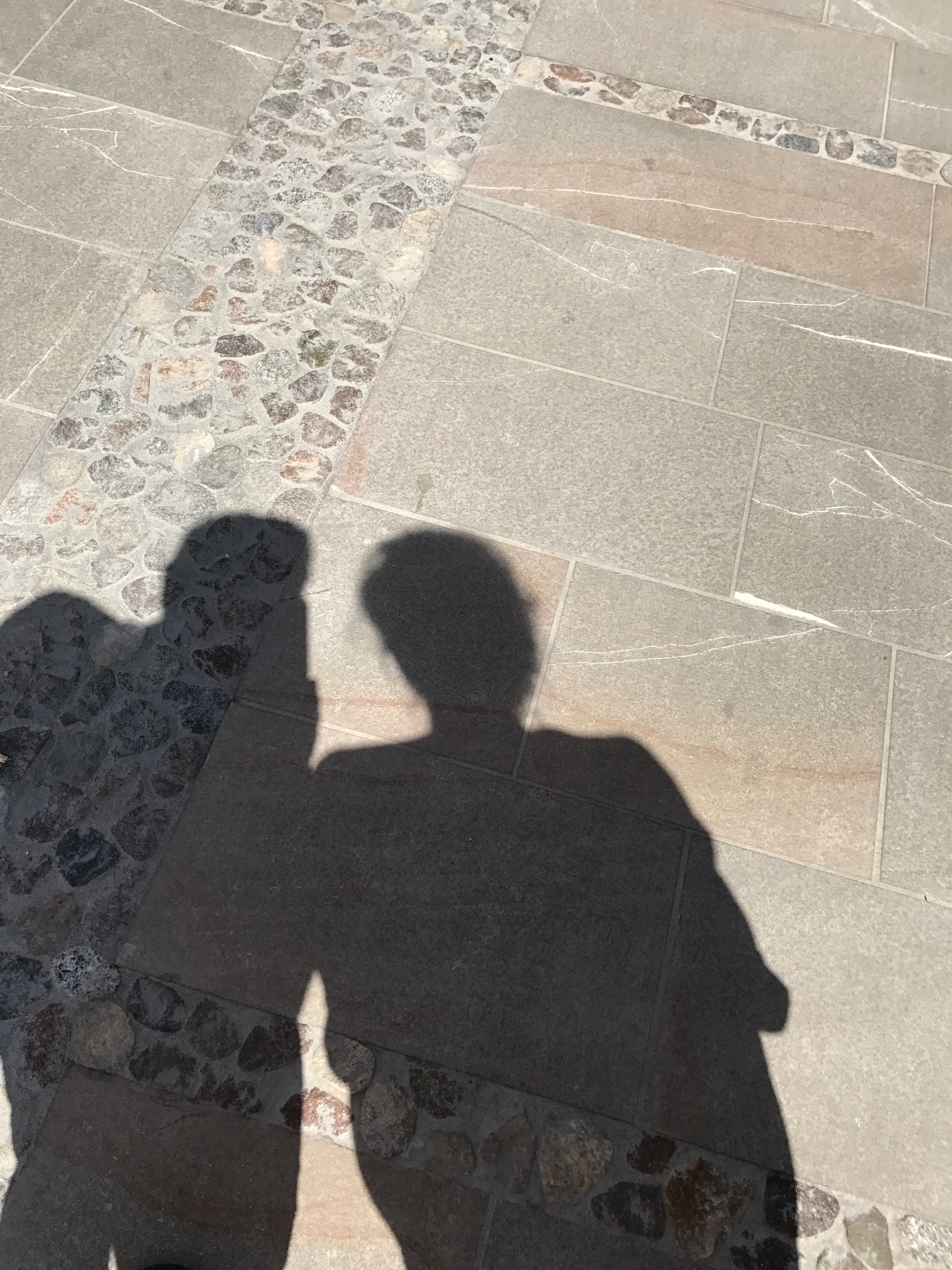 Cienie dwóch osób na kamiennej nawierzchni Piazza Grande w Palmanovie