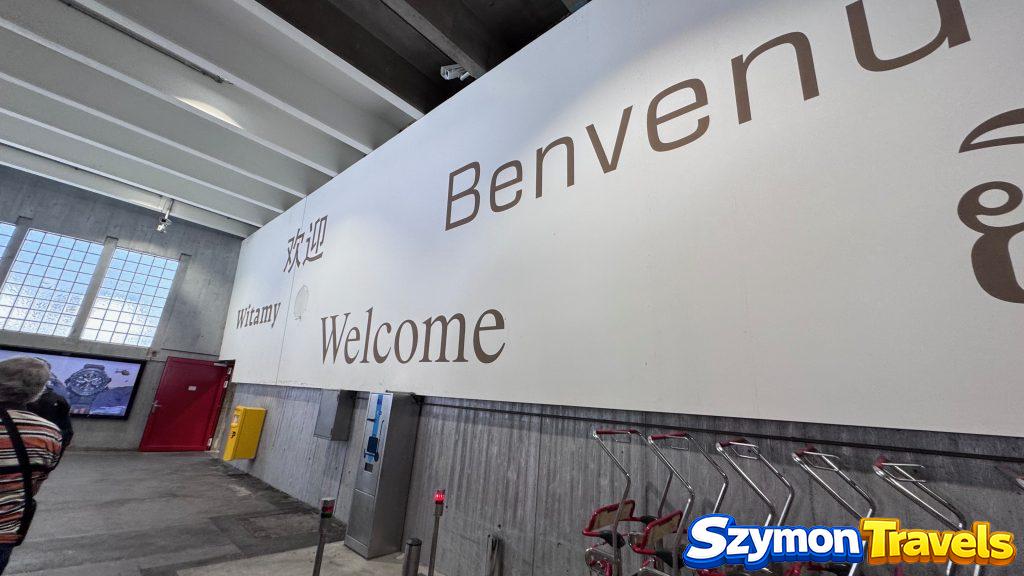 Matterhorn Terminal Täsch przed podróżą do Zermatt Wnętrze terminala w Täsch z dużym napisem Welcome i wózkami bagażowymi przed przejazdem pociągiem do Zermatt.