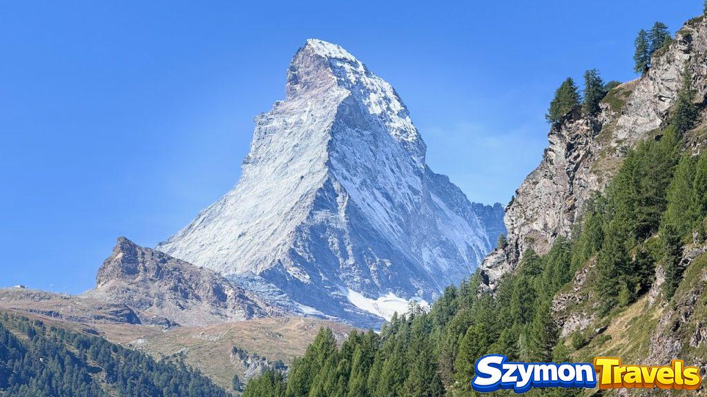 Matterhorn widziany z okolic Zermatt Matterhorn widziany z okolic Zermatt, z ostrym skalnym szczytem, śniegiem, lasem i błękitnym niebem.