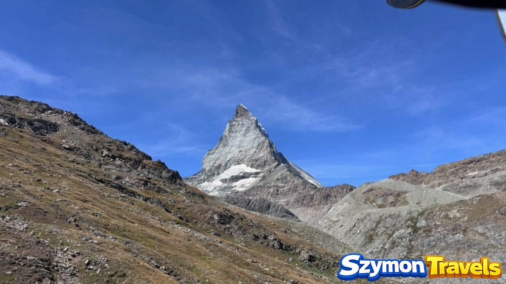 Matterhorn widziany z wysokości nad Zermatt Matterhorn widziany z kolejki lub górskiego terenu nad Zermatt, z surowymi skałami i błękitnym niebem.