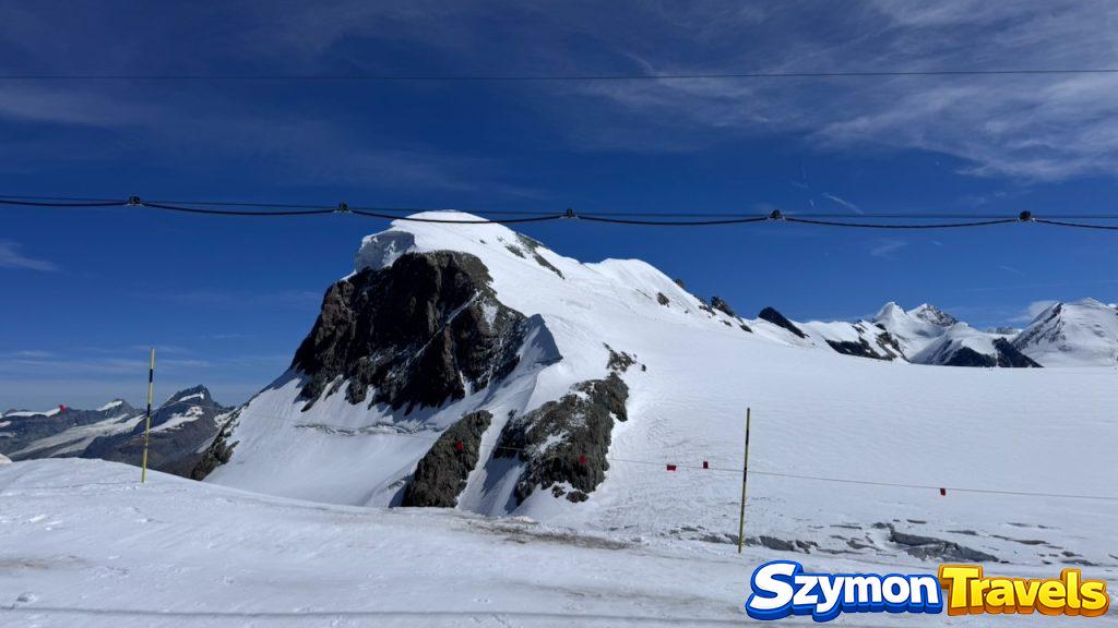 Wysokogórski teren przy Matterhorn Glacier Paradise, ze śniegiem, linami kolejki i lodowcowym krajobrazem.