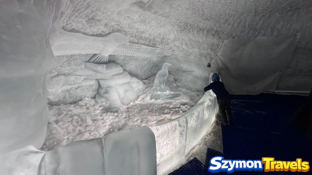 Lodowe rzeźby ptaka i łabędzia w Glacier Palace na Matterhorn Glacier Paradise, z turystą przy barierze.