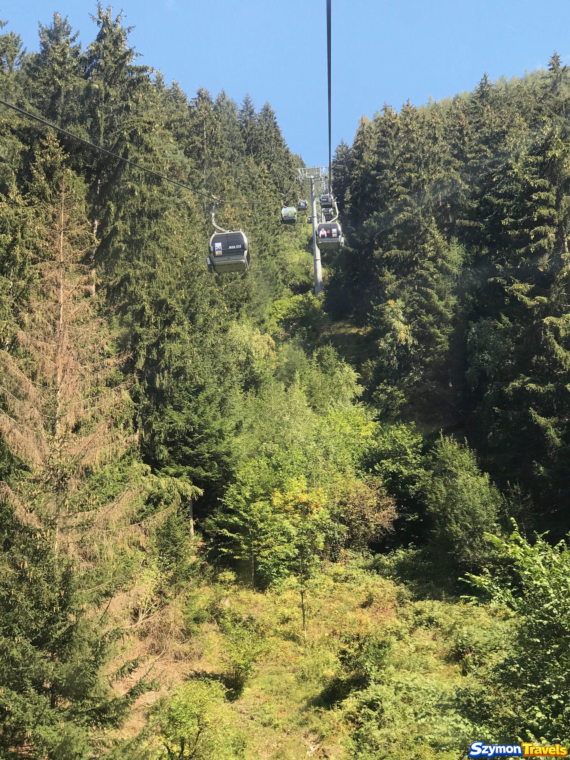 Acherkogelbahn z Oetz do Hochoetz Gondole Acherkogelbahn jadące nad zielonym lasem i stromym zboczem z Oetz w stronę Hochoetz.
