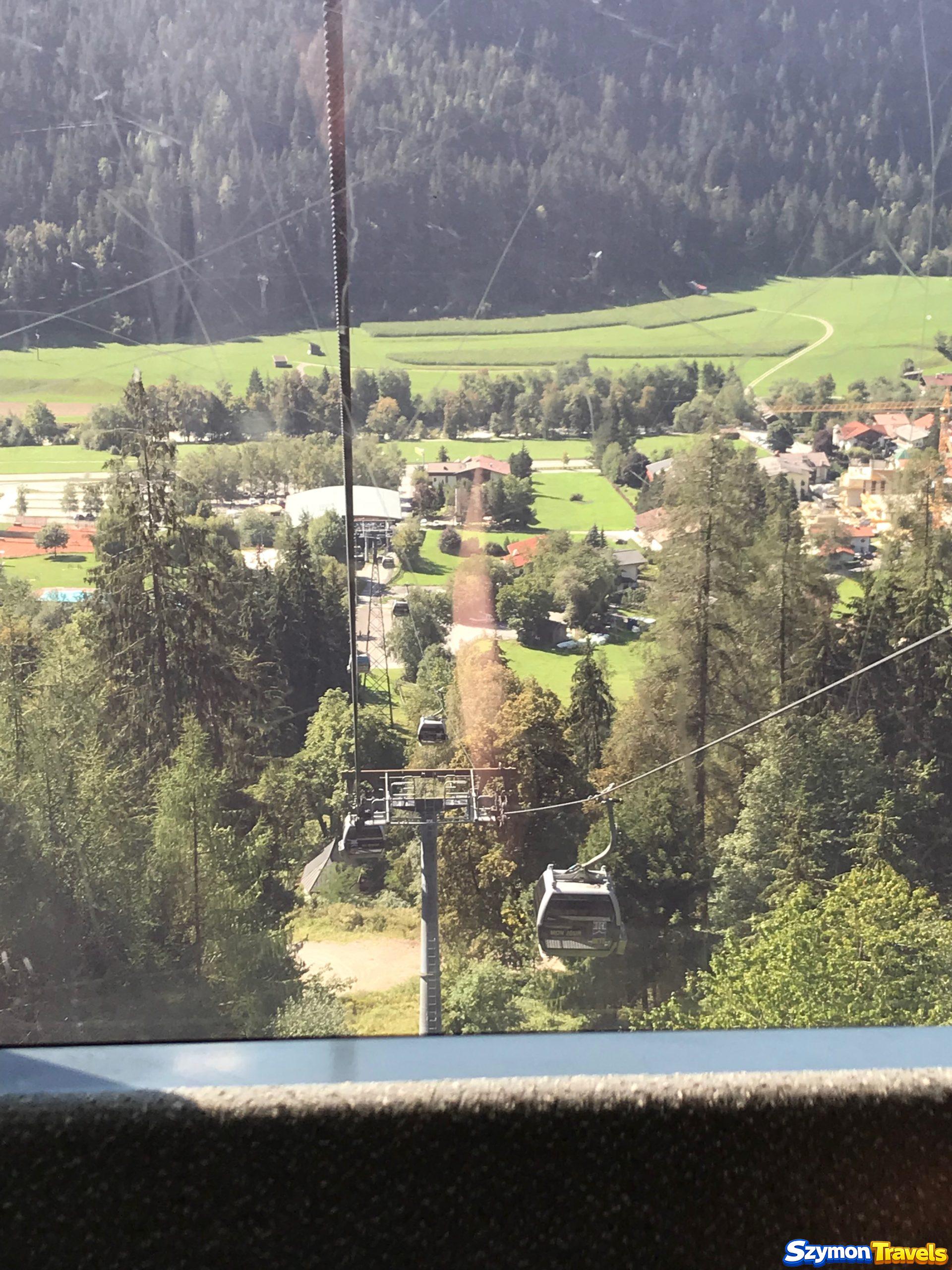 Widok z Acherkogelbahn na Oetz i dolinę Widok z gondoli Acherkogelbahn w dół na Oetz, stację kolejki, pola, lasy i zabudowania doliny Ötztal.
