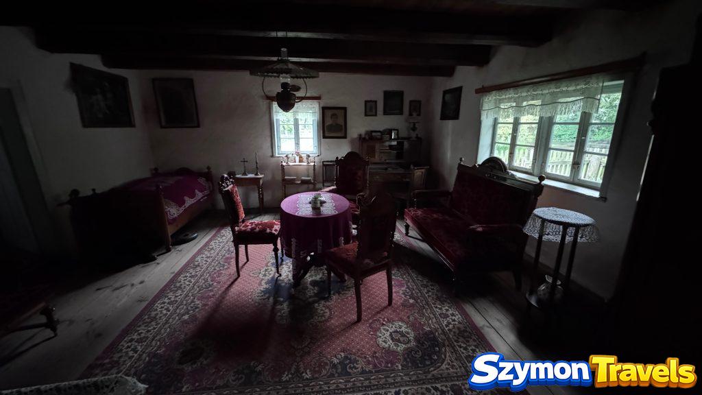 Ciemna izba z łóżkiem, stołem i drewnianymi meblami w Muzeum Wsi Opolskiej