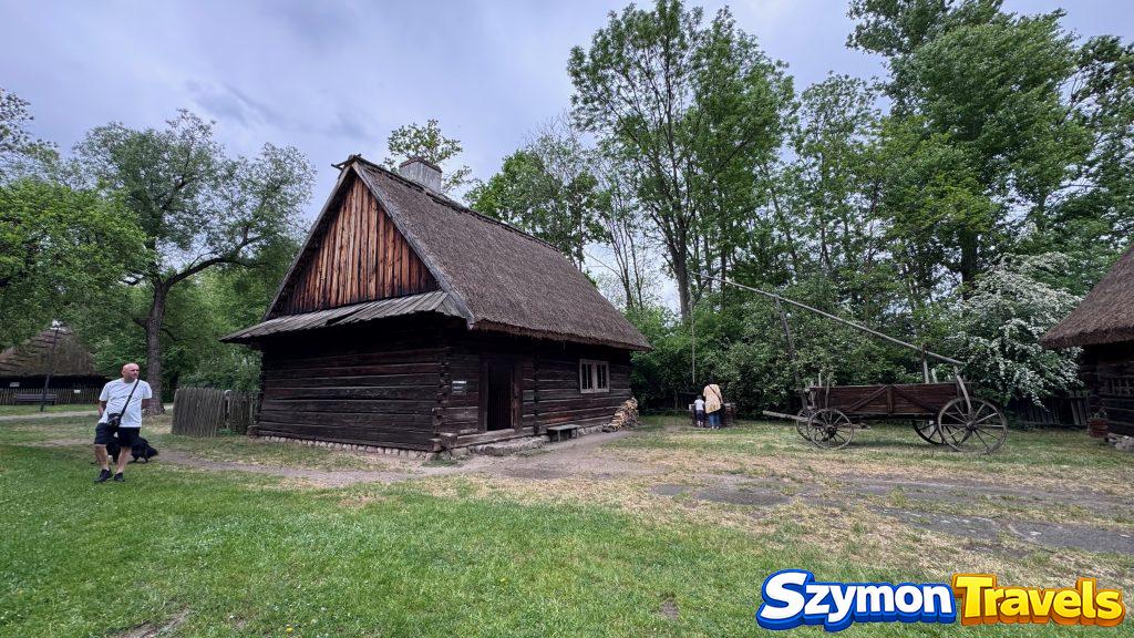 Drewniana chałupa kryta strzechą i wóz w Muzeum Wsi Opolskiej