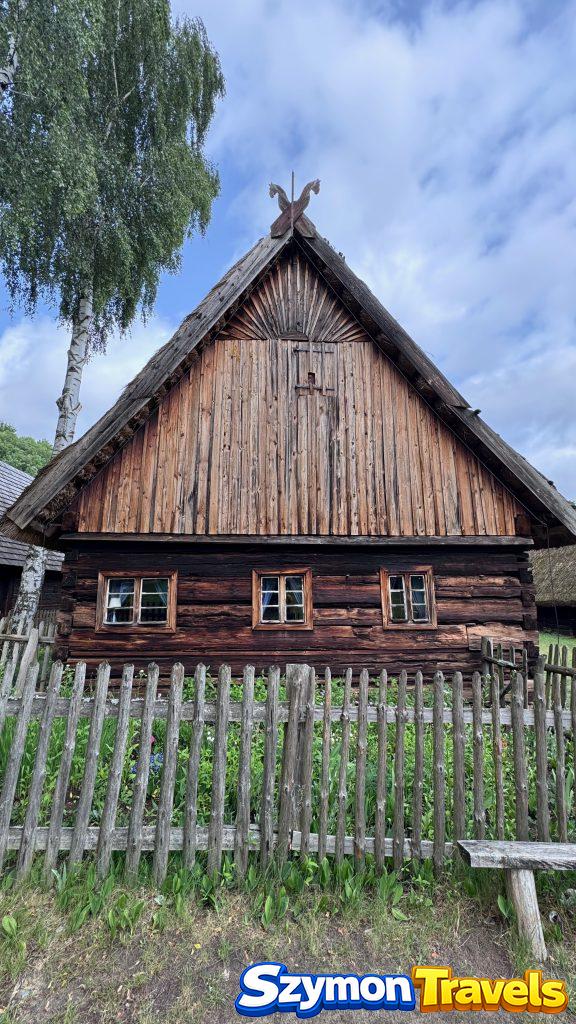 Drewniana chałupa z wysokim szczytem i płotem w Muzeum Etnograficznym w Zielonej Górze-Ochli