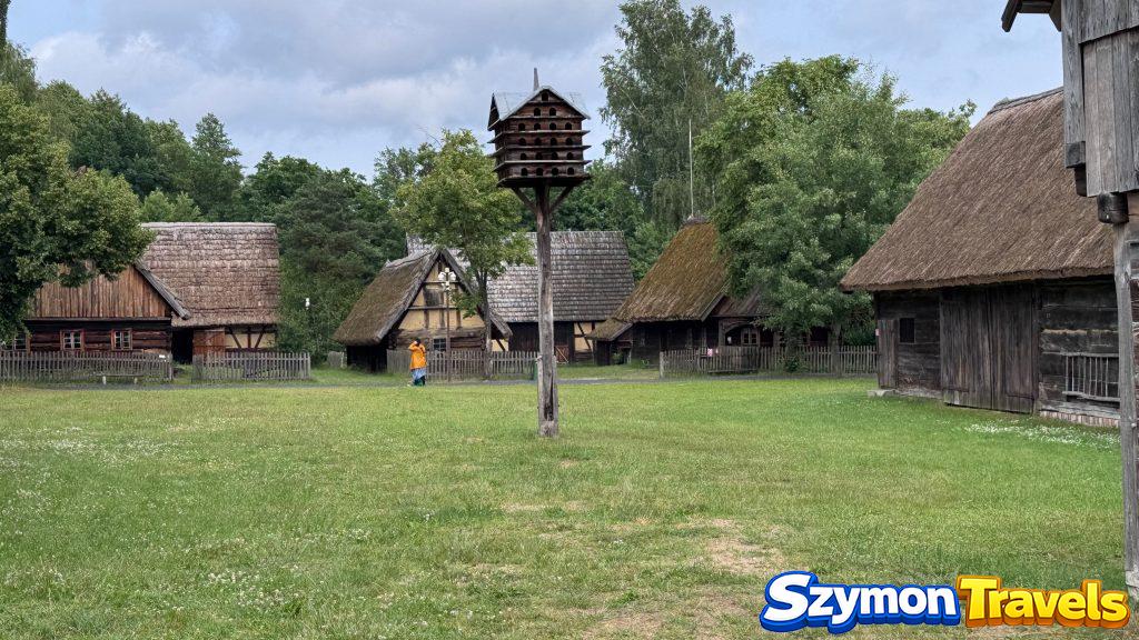 Panorama Muzeum Etnograficznego w Zielonej Górze-Ochli z drewnianymi chałupami, gołębnikiem i zielonym placem