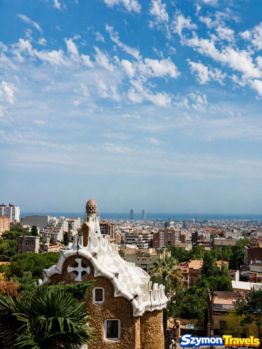Pawilon wejściowy Park Güell z dekoracyjnym dachem oraz panoramą Barcelony i morza w tle