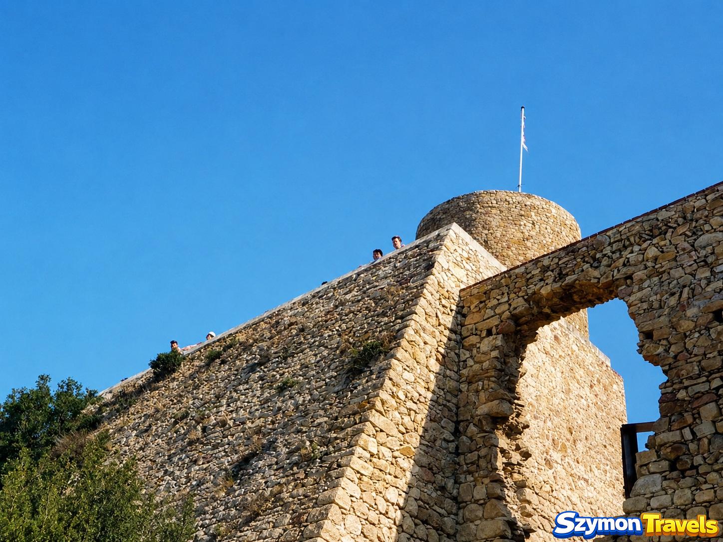 Kamienne mury i wieża Castell de Sant Joan w Blanes widziane od dołu w ostrym sierpniowym słońcu