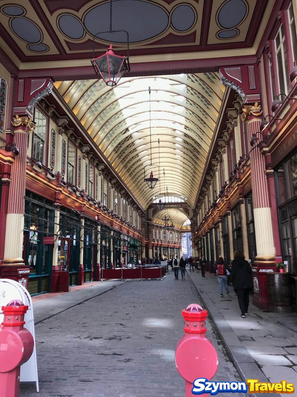 Wnętrze Leadenhall Market z wiktoriańskim szklanym dachem, czerwonymi kolumnami i brukowaną ulicą
