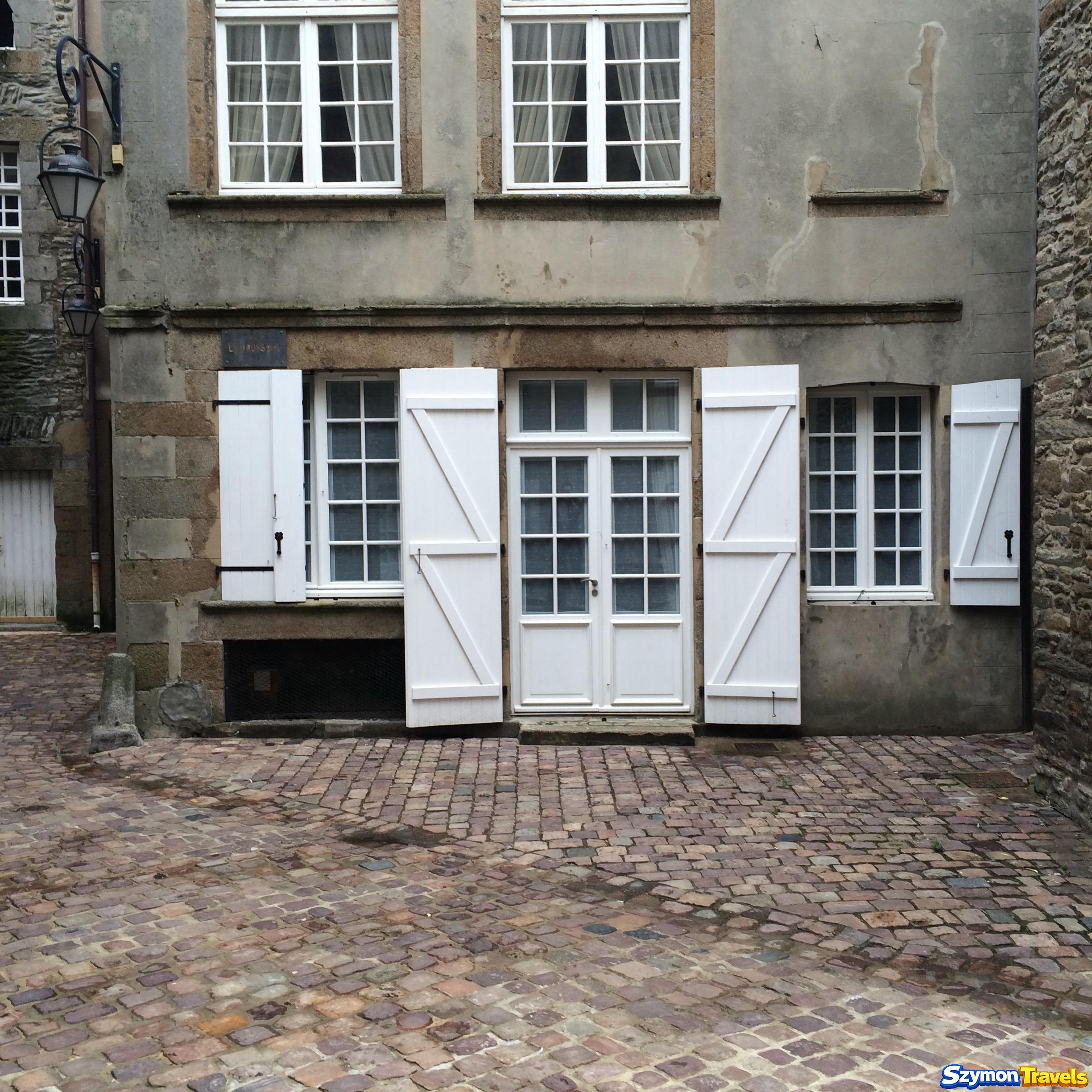 Kamienna fasada domu z białymi okiennicami w Saint-Malo Intra-Muros