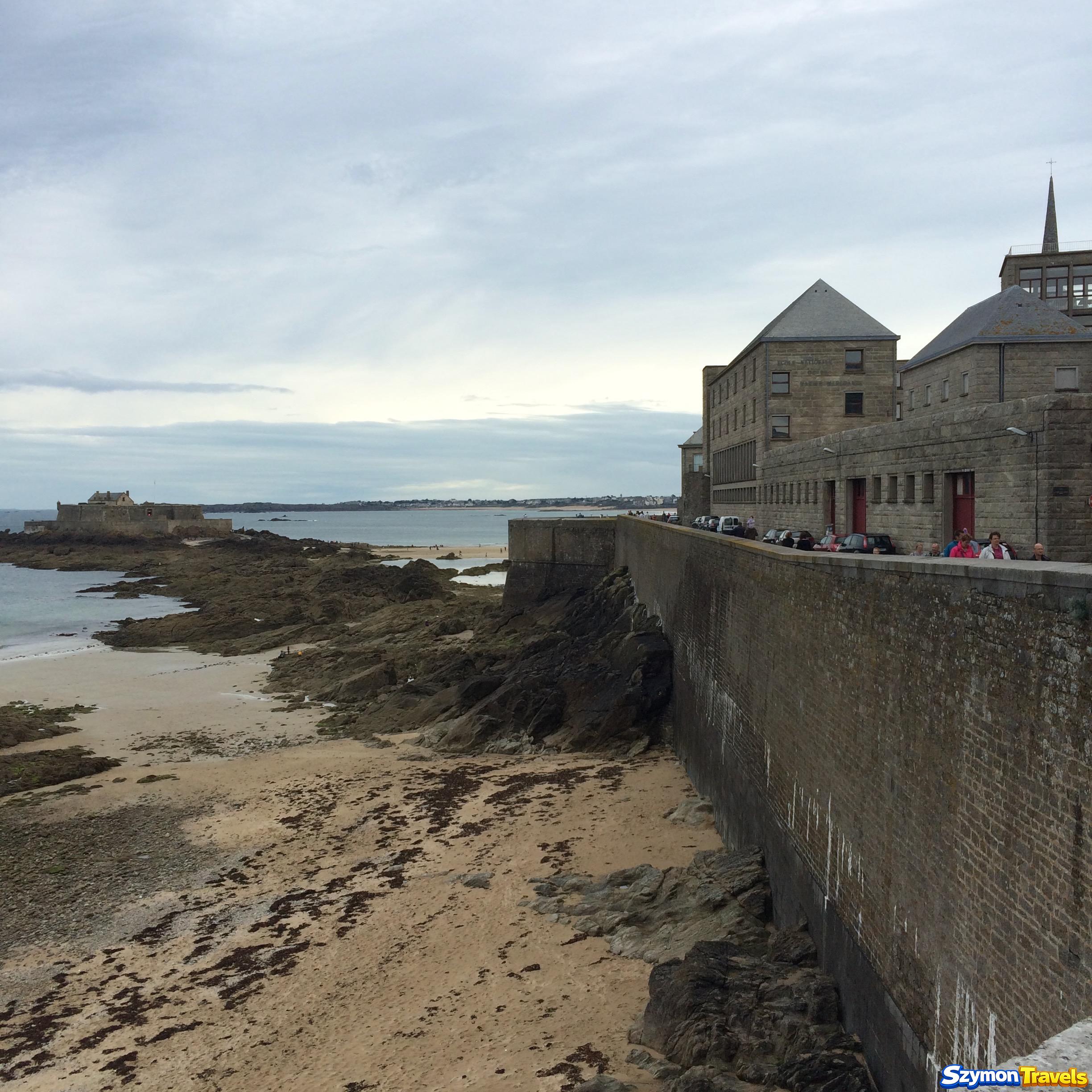 Potężne kamienne mury Saint-Malo nad plażą, skałami i morzem w Bretanii