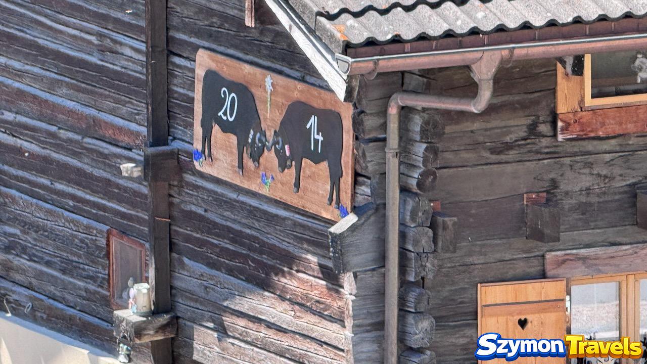 Tablica z krowami rasy Hérens na drewnianym domu w Les Haudères