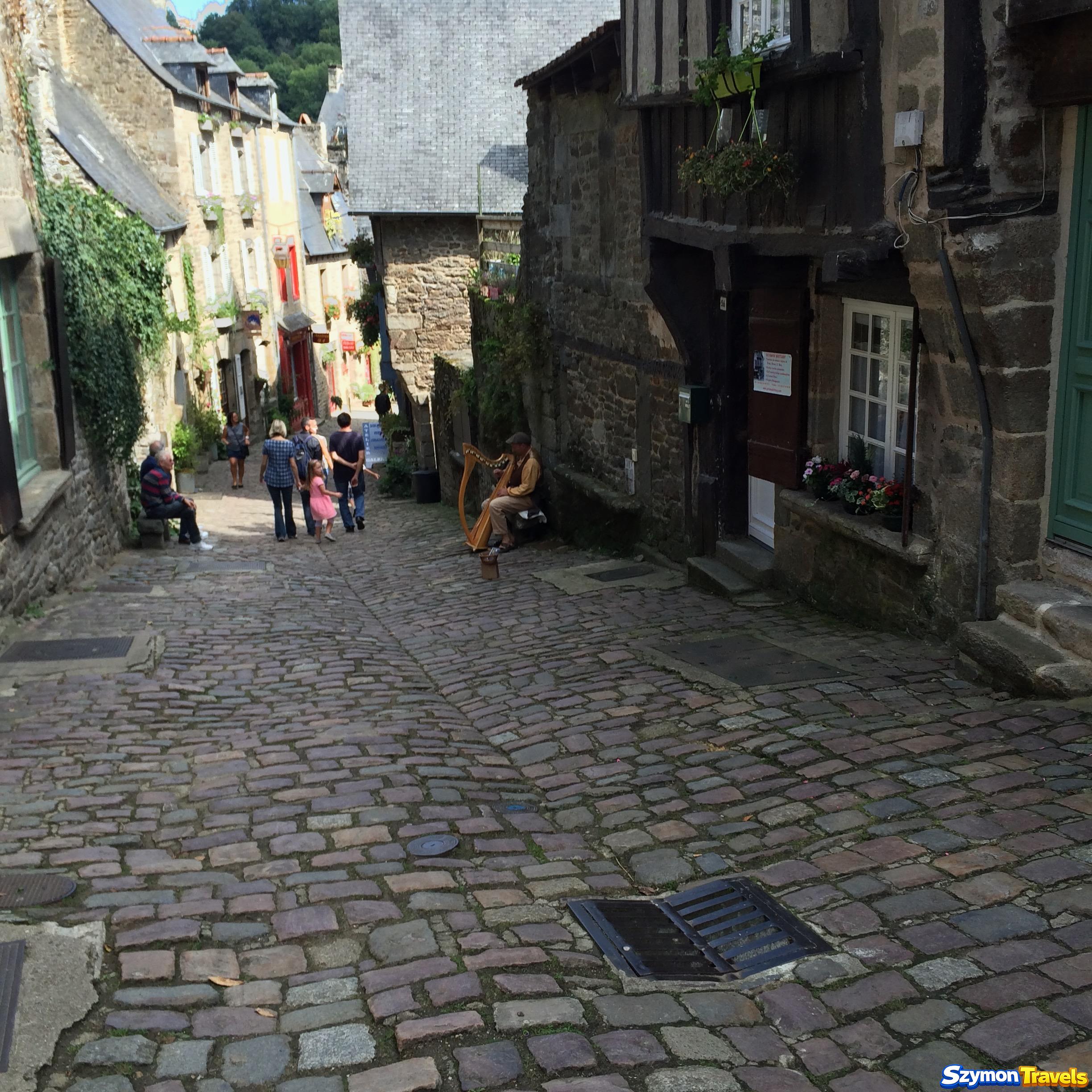 Harfista grający na brukowanej ulicy Rue du Jerzual w Dinan