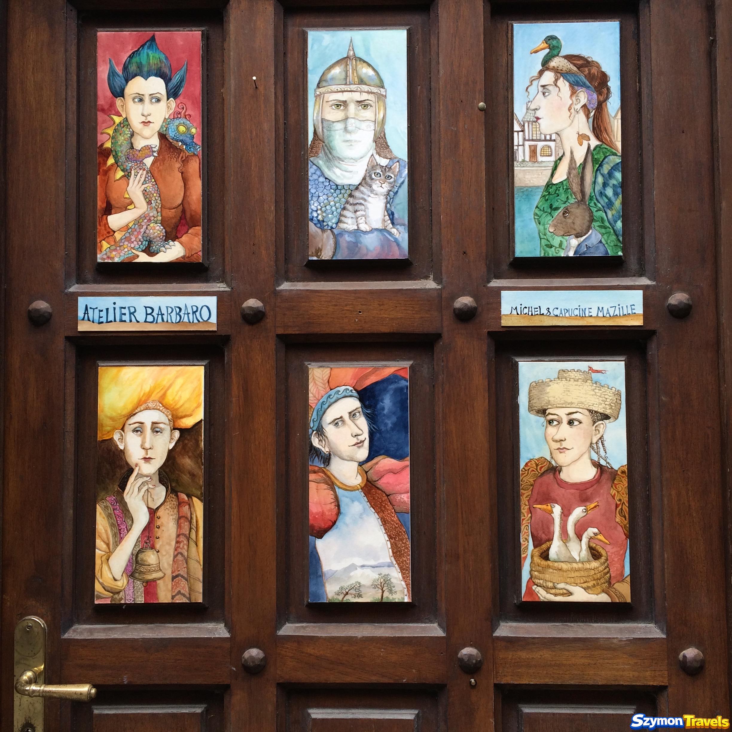 Kolorowe portrety eksponowane na drewnianych drzwiach Atelier Barbaro w Dinan