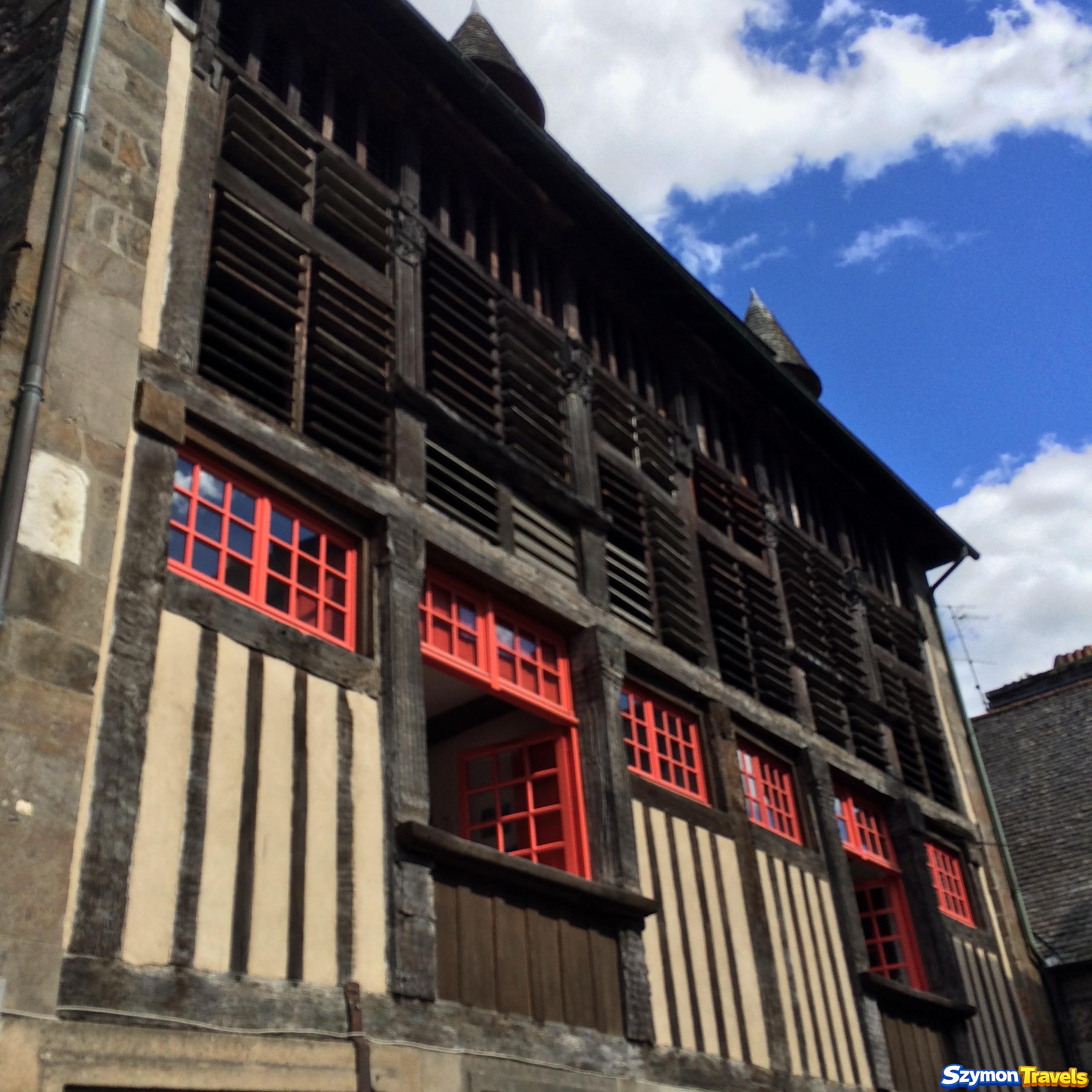Wysoki historyczny dom szkieletowy z czerwonymi oknami w Dinan