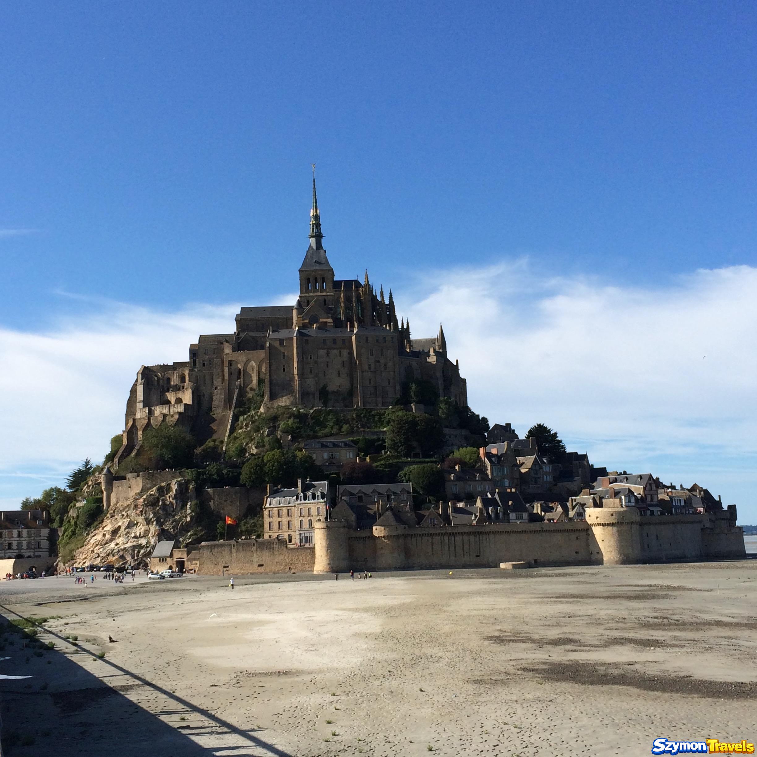 Mont-Saint-Michel widziany podczas odpływu z szeroką przestrzenią piasku przed murami