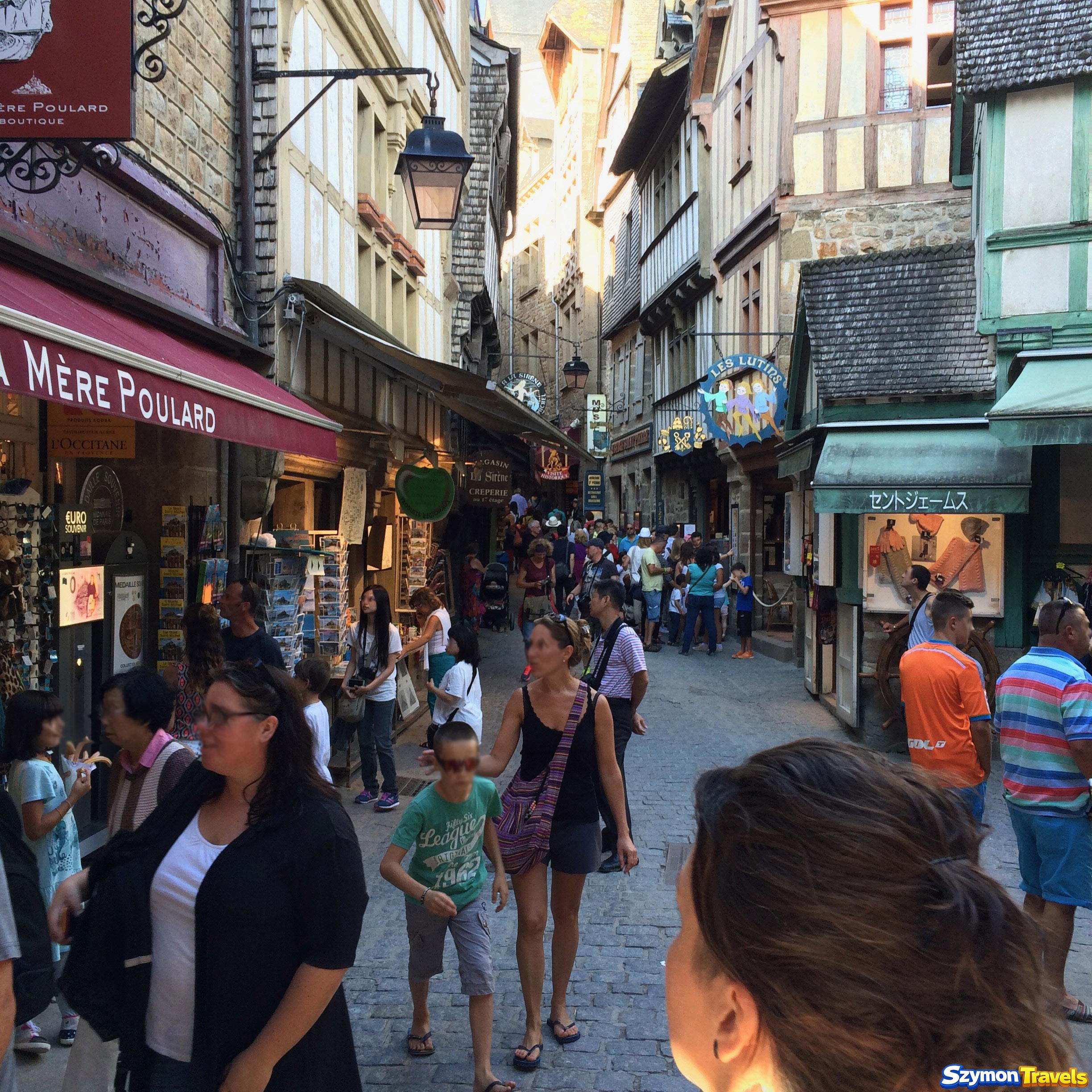 Tłum odwiedzających na wąskiej Grande Rue w miasteczku Mont-Saint-Michel