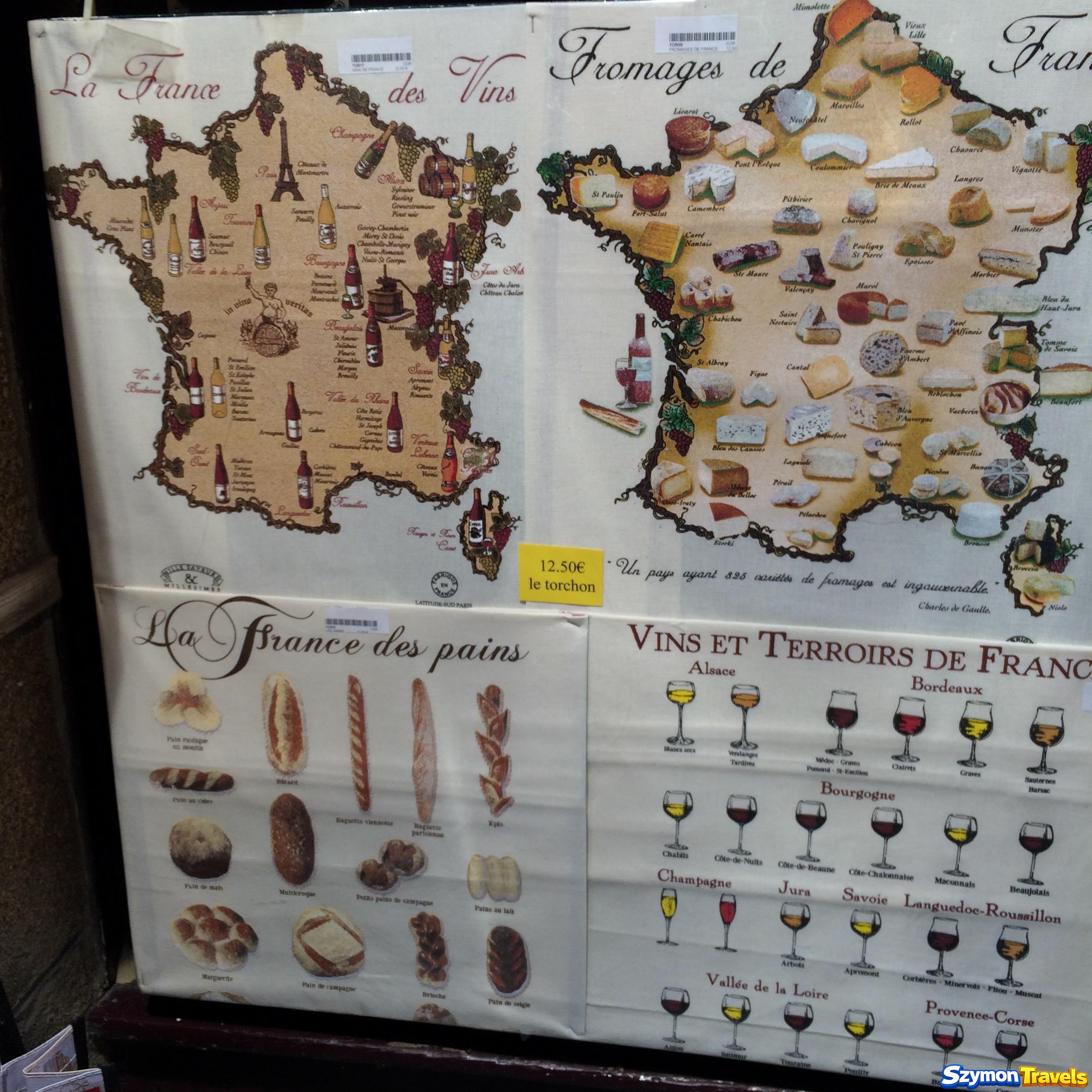 Tekstylia z mapami francuskich serów, win i pieczywa w sklepie na Mont-Saint-Michel