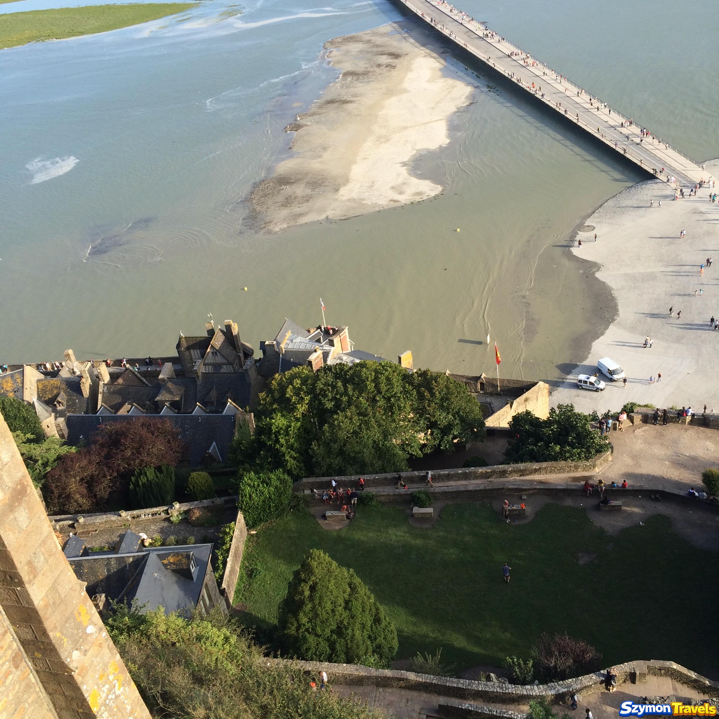 Wejście na most-kładkę i zalane fragmenty zatoki przy Mont-Saint-Michel widziane z góry