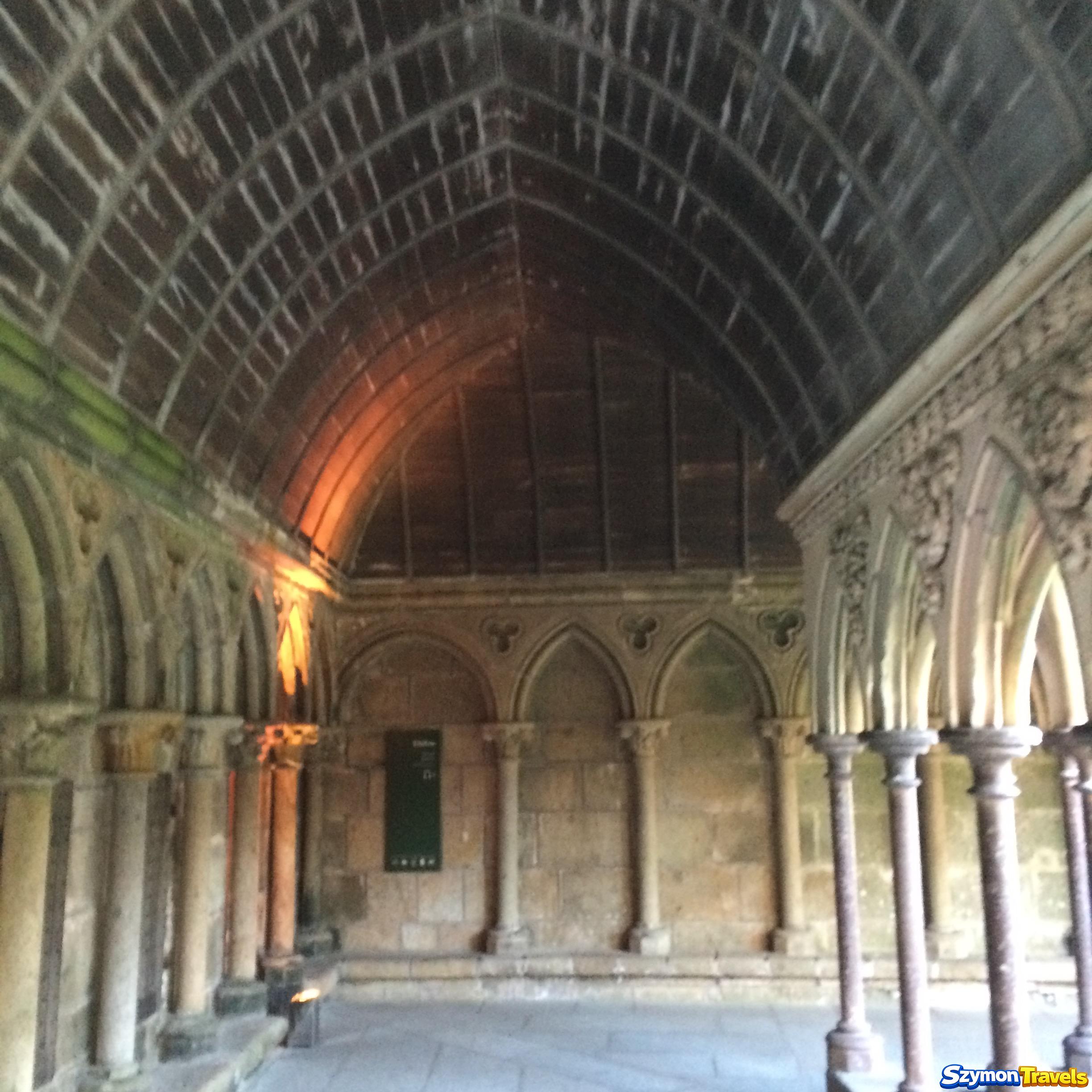Kryta galeria krużganka z kamiennymi arkadami i sklepieniem w opactwie Mont-Saint-Michel