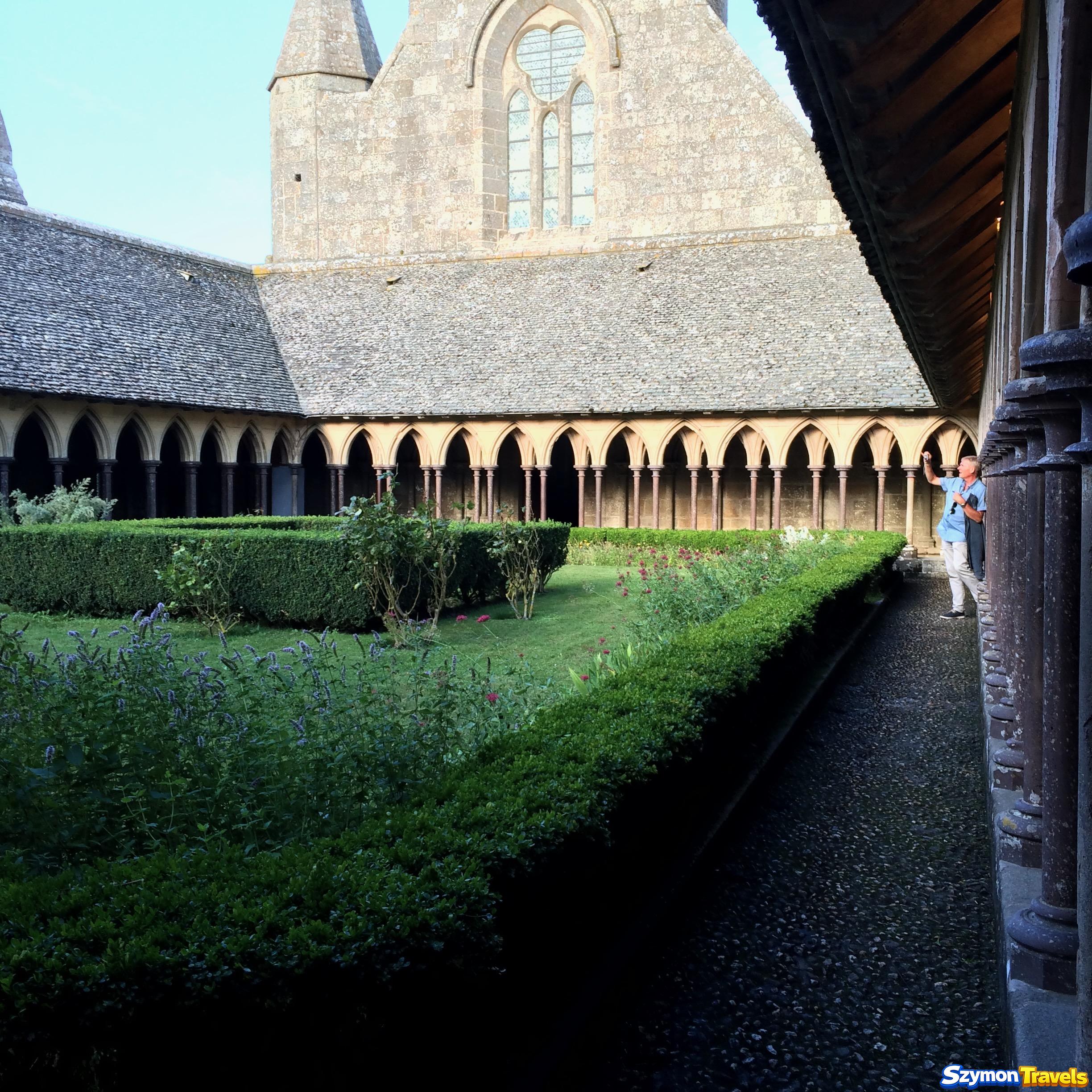 Krużganek opactwa Mont-Saint-Michel z ogrodem i smukłymi kamiennymi arkadami